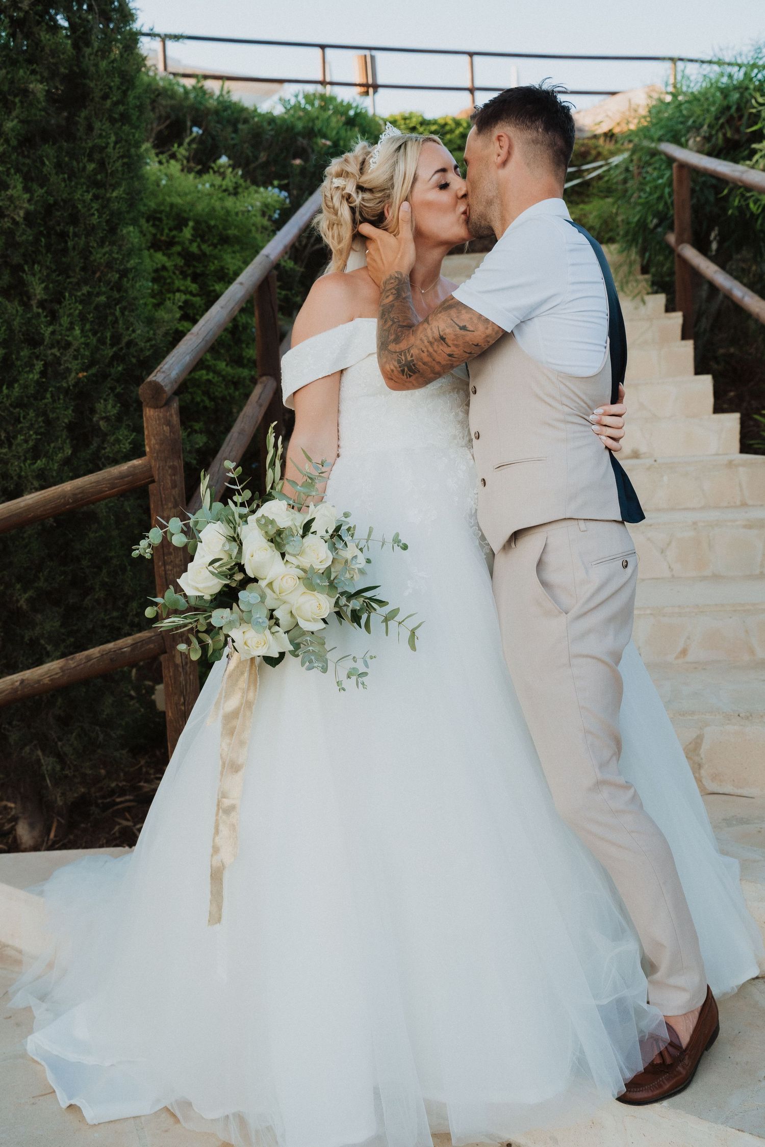 Romantic moment captured on rustic wooden staircase with greenery background.