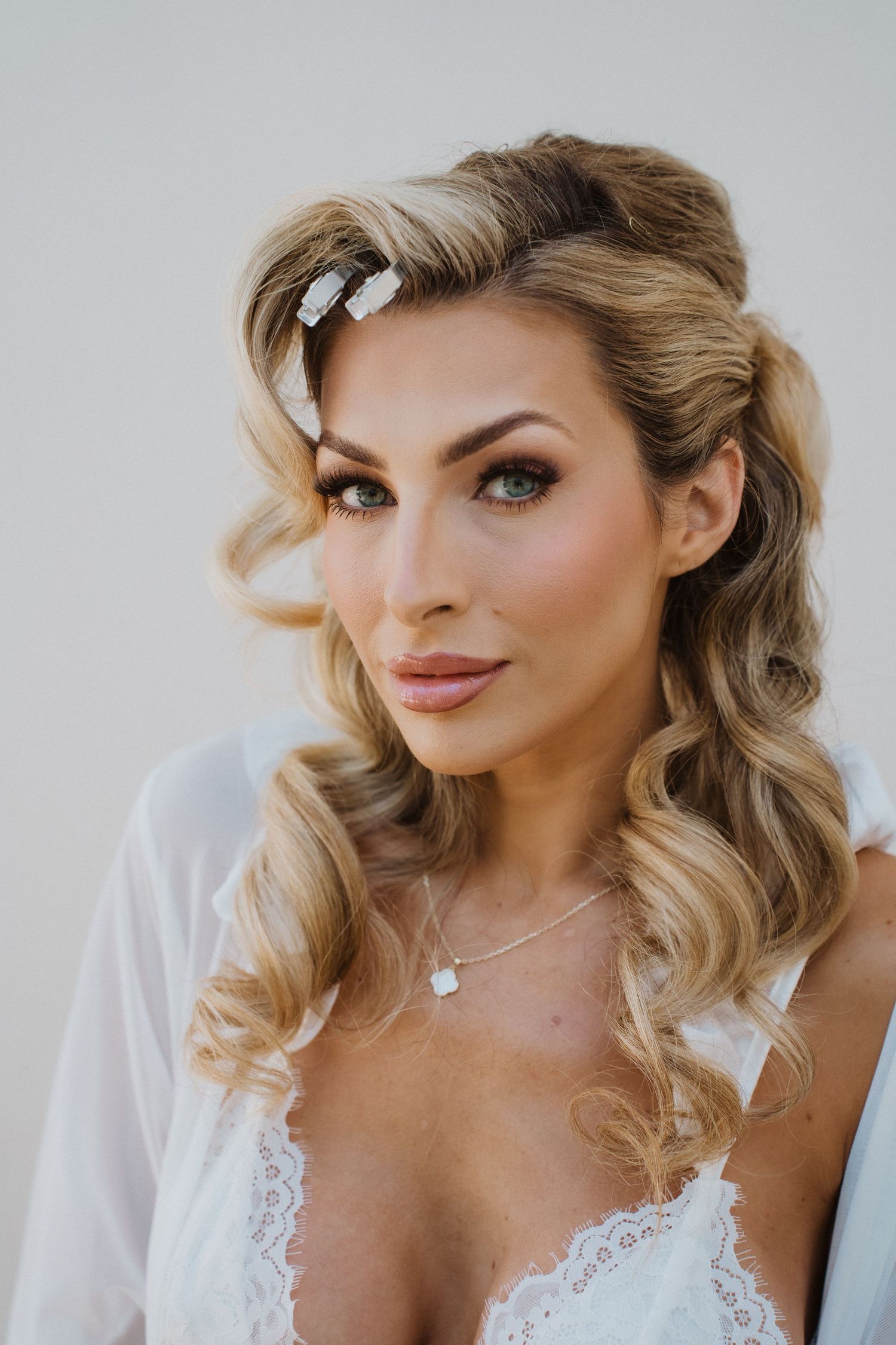 Close up beauty shot of blonde wavy hair with pearl hair clip and lace dress detail.