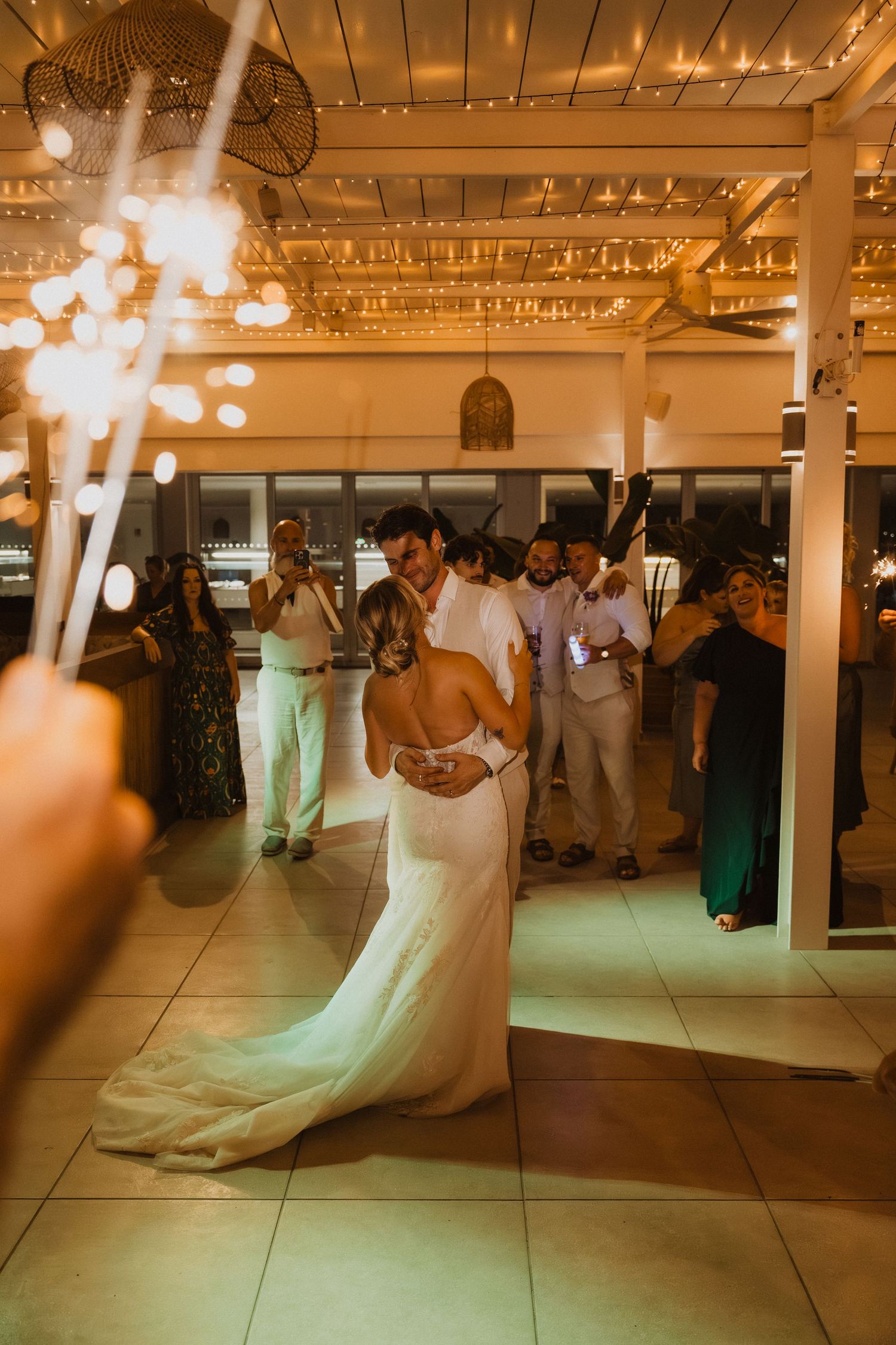 Wedding reception dance floor scene with sparklers and string lights creating magical ambiance.