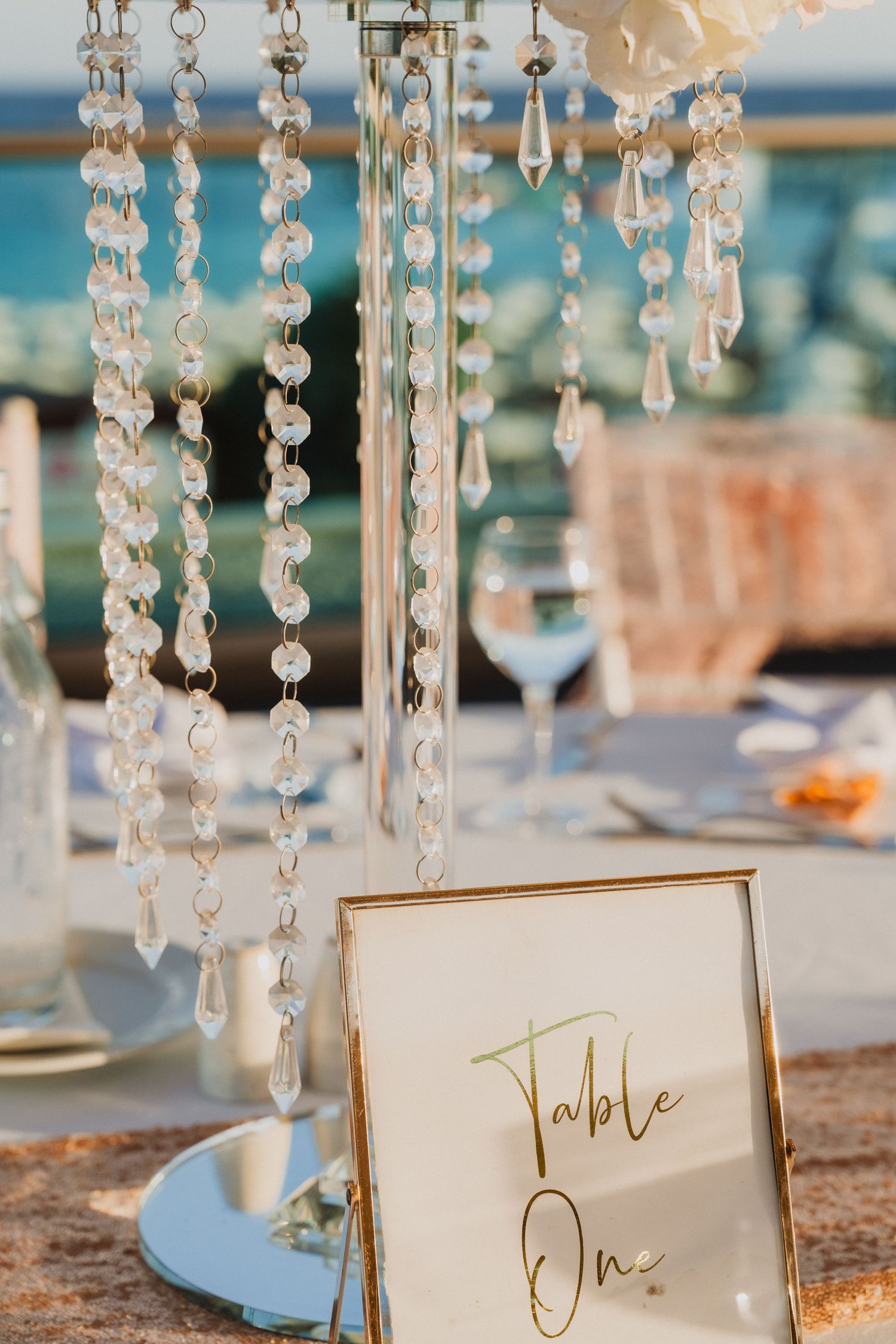 Elegant table setting with crystal chandelier and gold-framed Table One sign.
