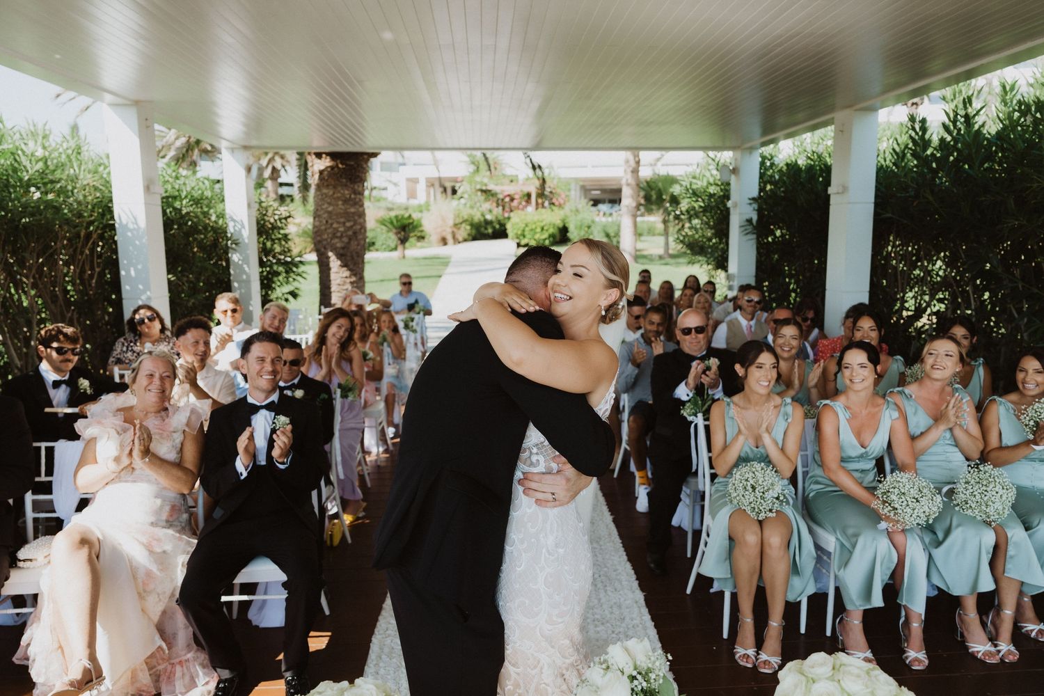 Wedding party and guests gather on a covered porch for celebration photos.