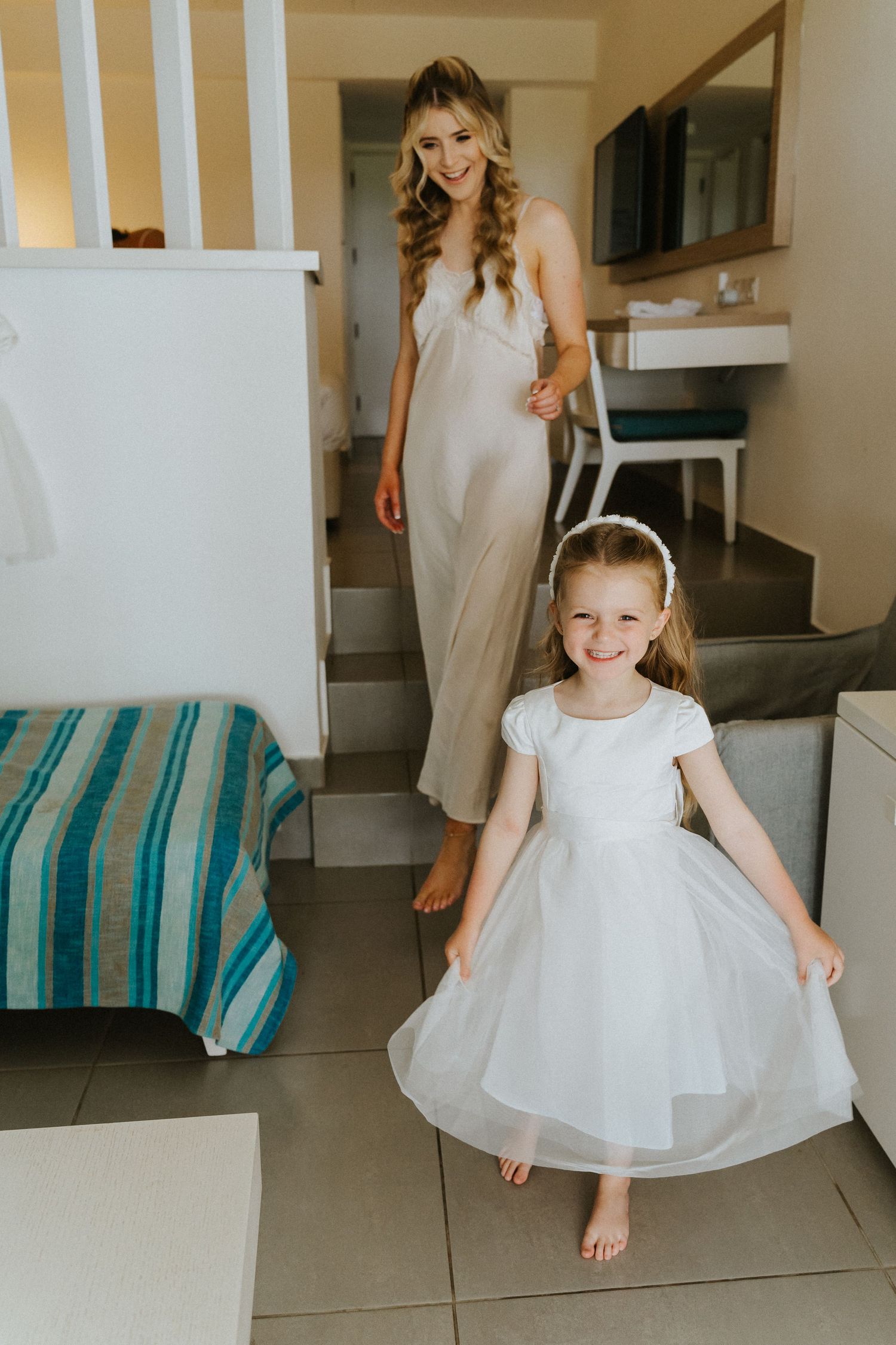 Two people in white dresses standing on stairs in a modern interior.