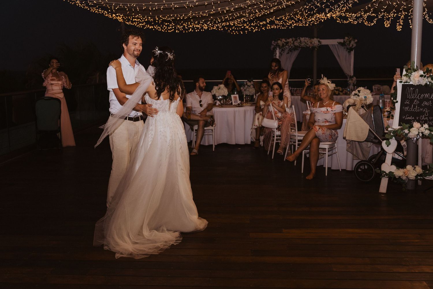 A romantic first dance at an outdoor wedding reception under string lights.
