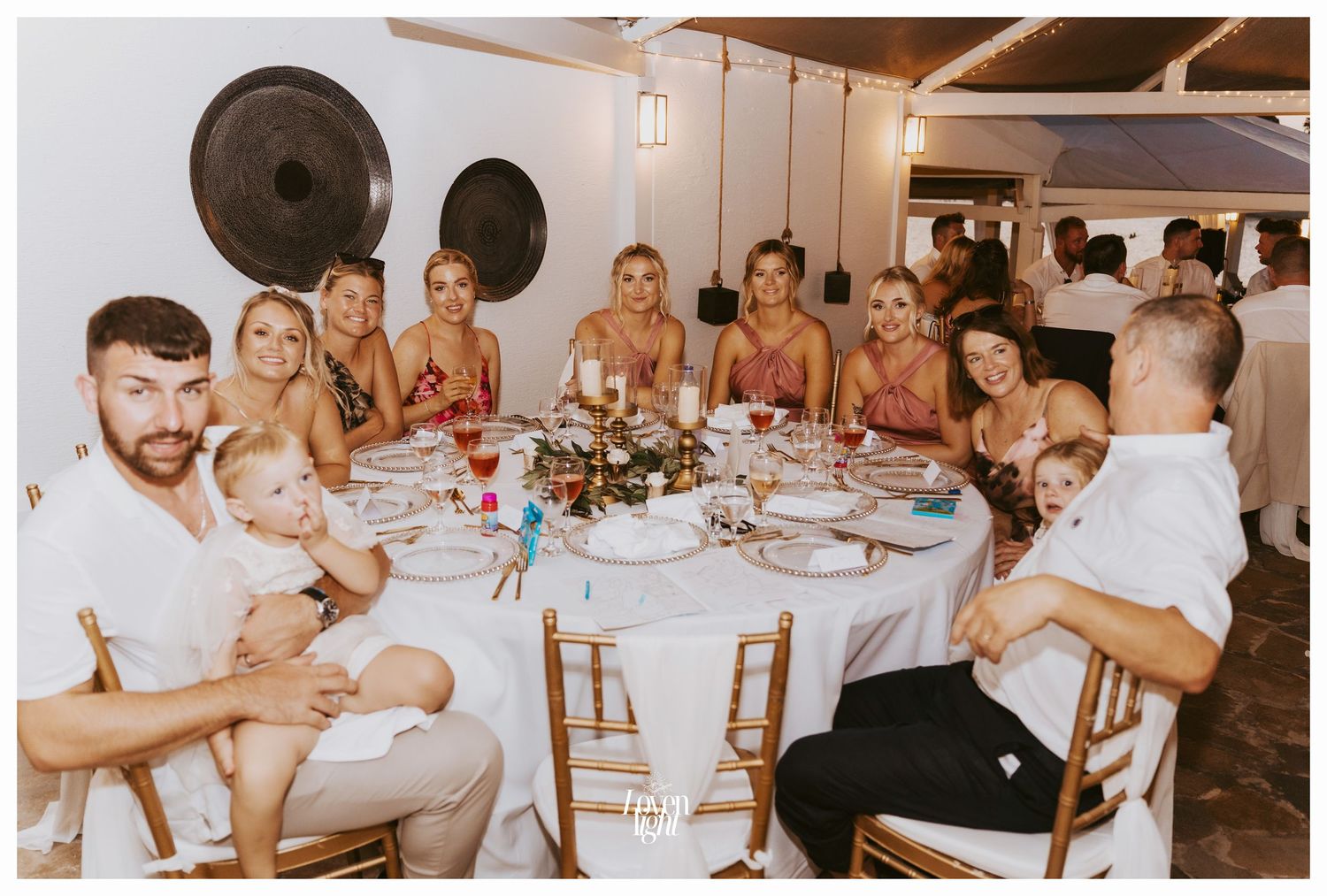 Wedding party gathered around a circular table at an indoor reception venue.