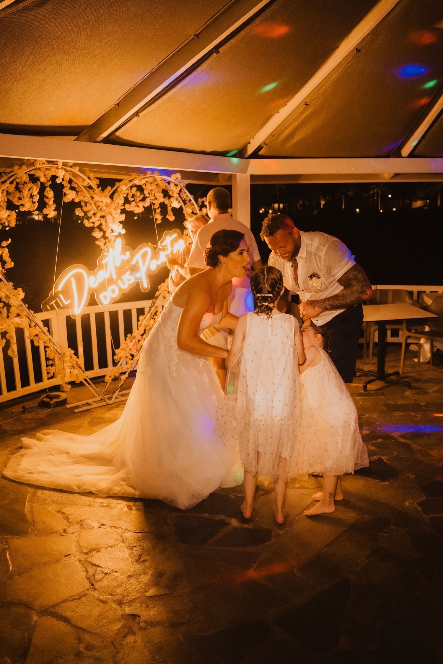A candlelit wedding reception moment under glowing string lights and floral decorations.