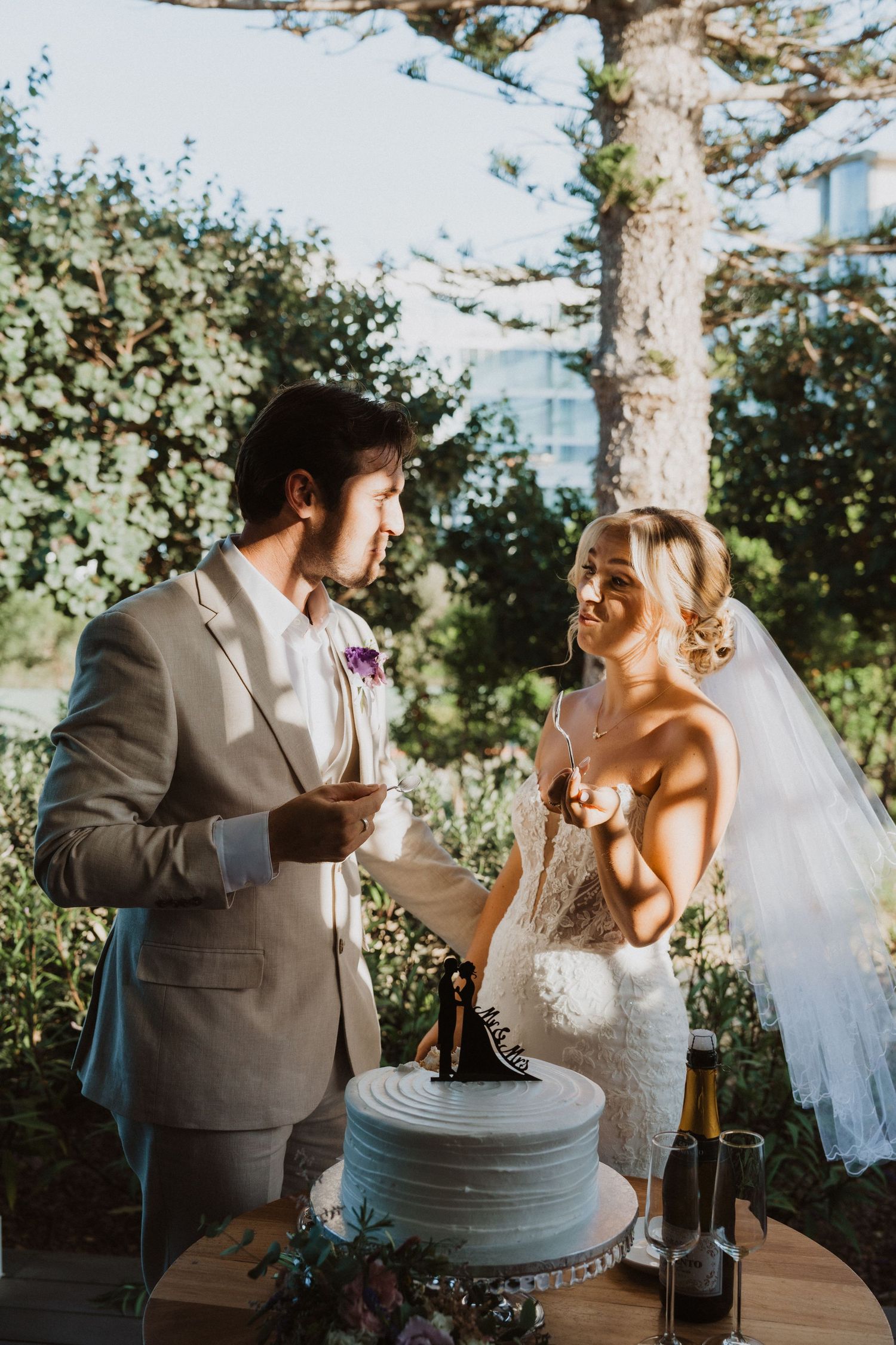 Couple enjoys a playful cake cutting moment at their outdoor wedding reception.