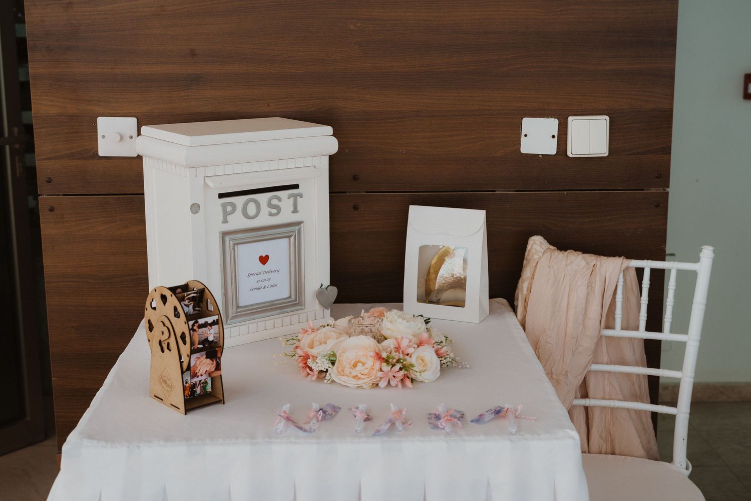 White decorative post box with floral arrangements and delicate accessories on wooden background.