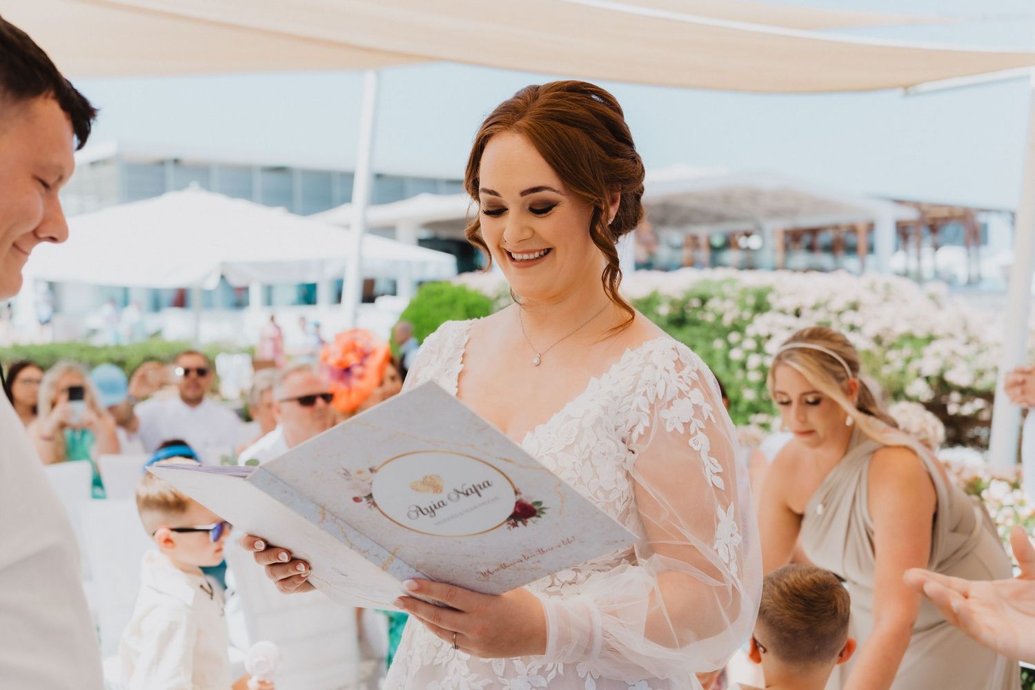 A couple shares documents during their outdoor wedding ceremony by the beach.