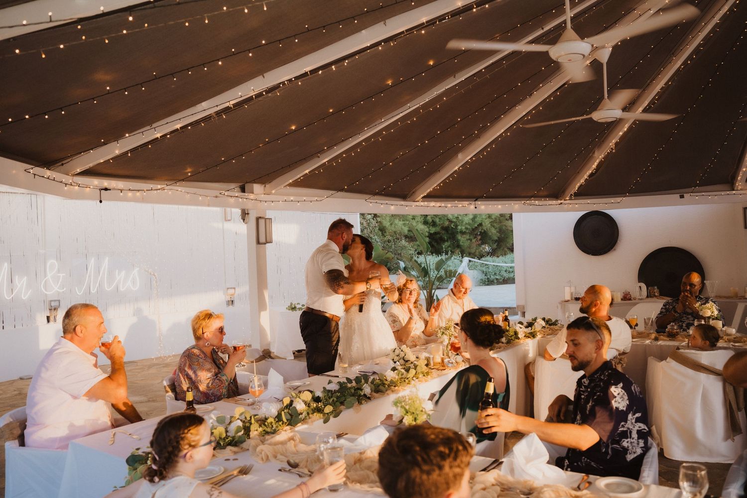 Wedding reception under white tent with string lights and decorated tables.
