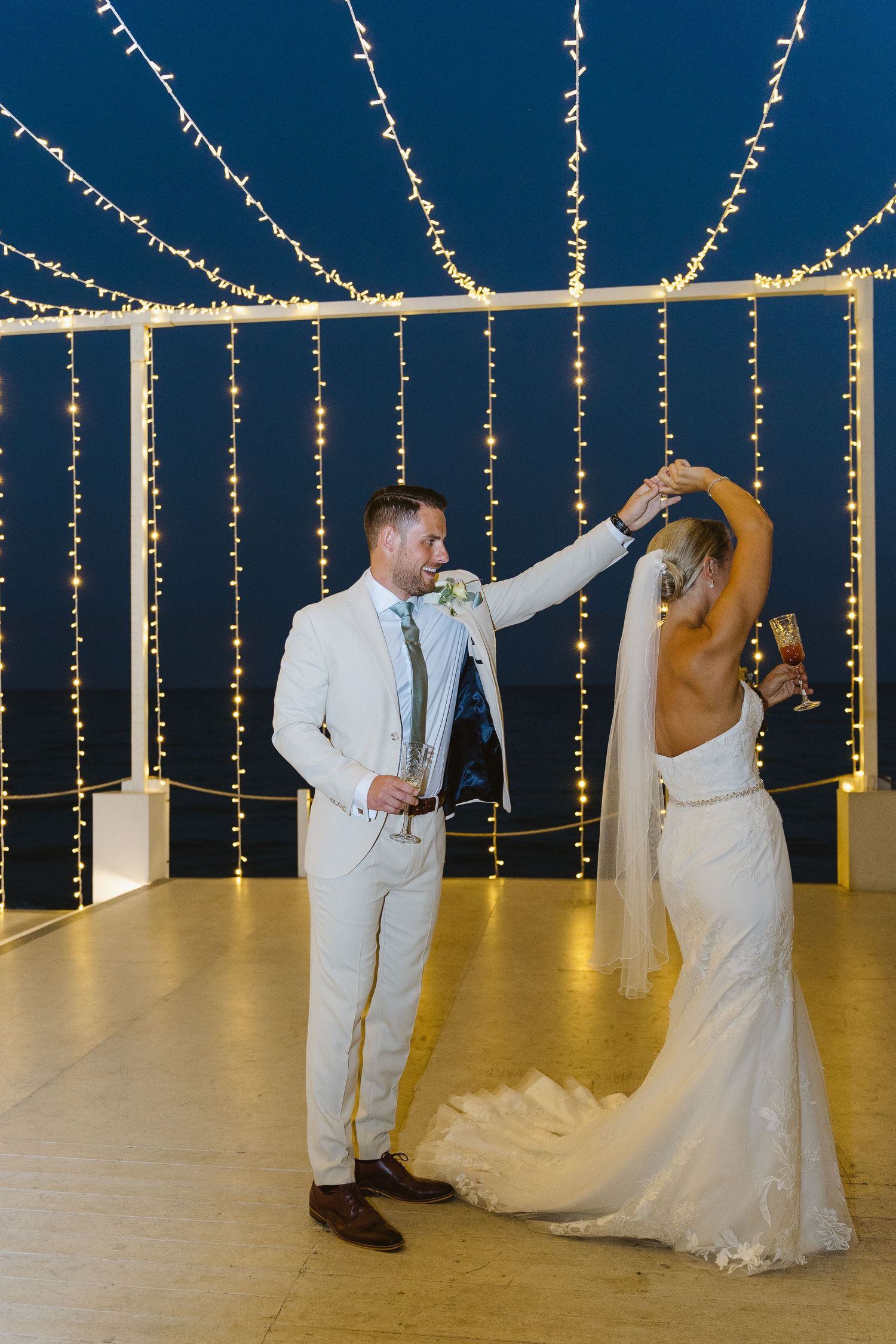 Couple shares a romantic dance under cascading string lights at their wedding reception.