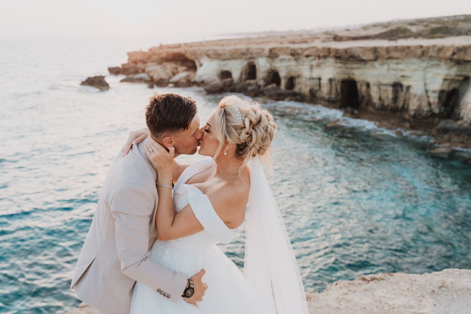 A romantic wedding moment captured on scenic ocean cliffs during sunset.