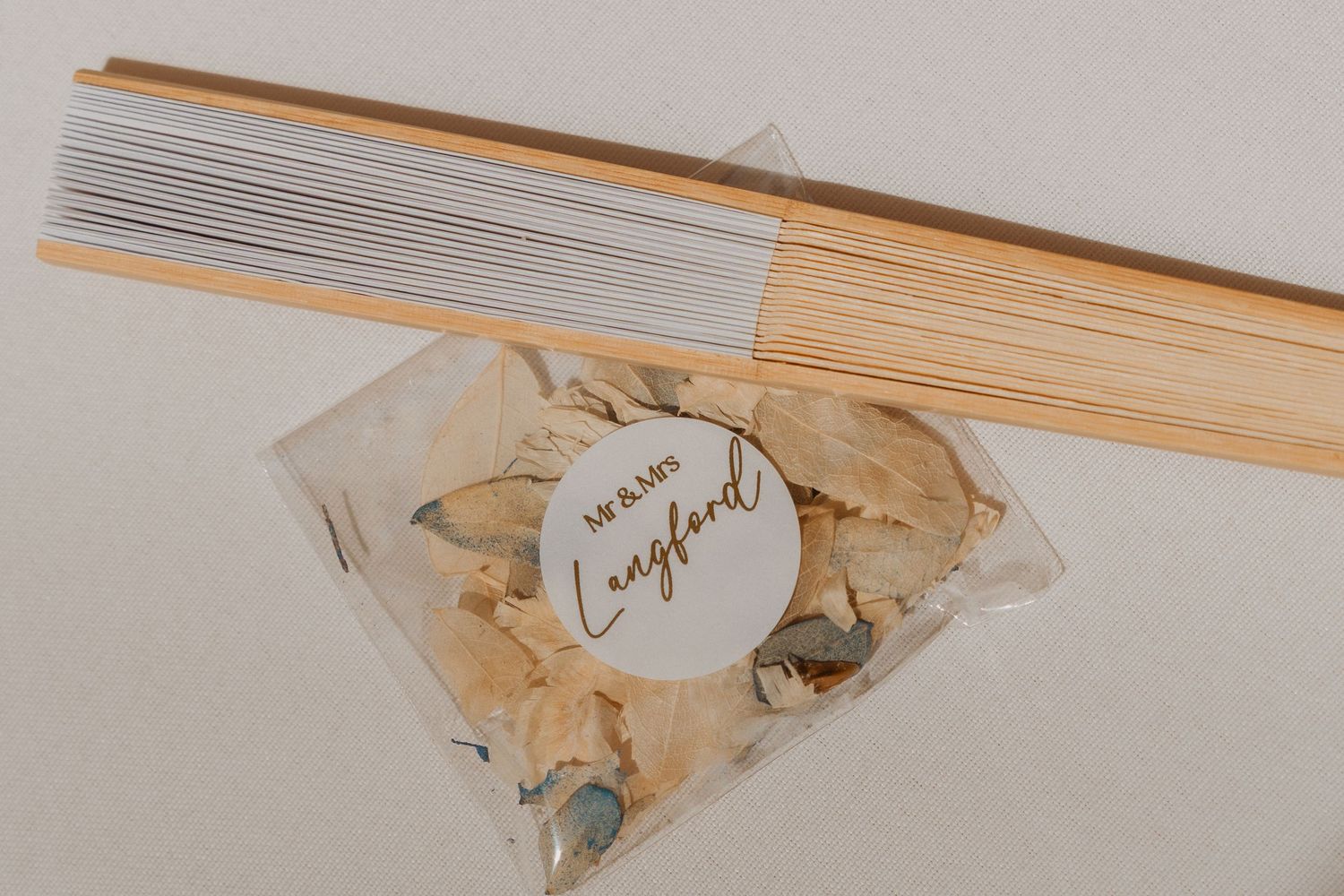 Elegant wedding confetti bag with dried flowers and a personalized label, displayed with reed diffuser sticks.