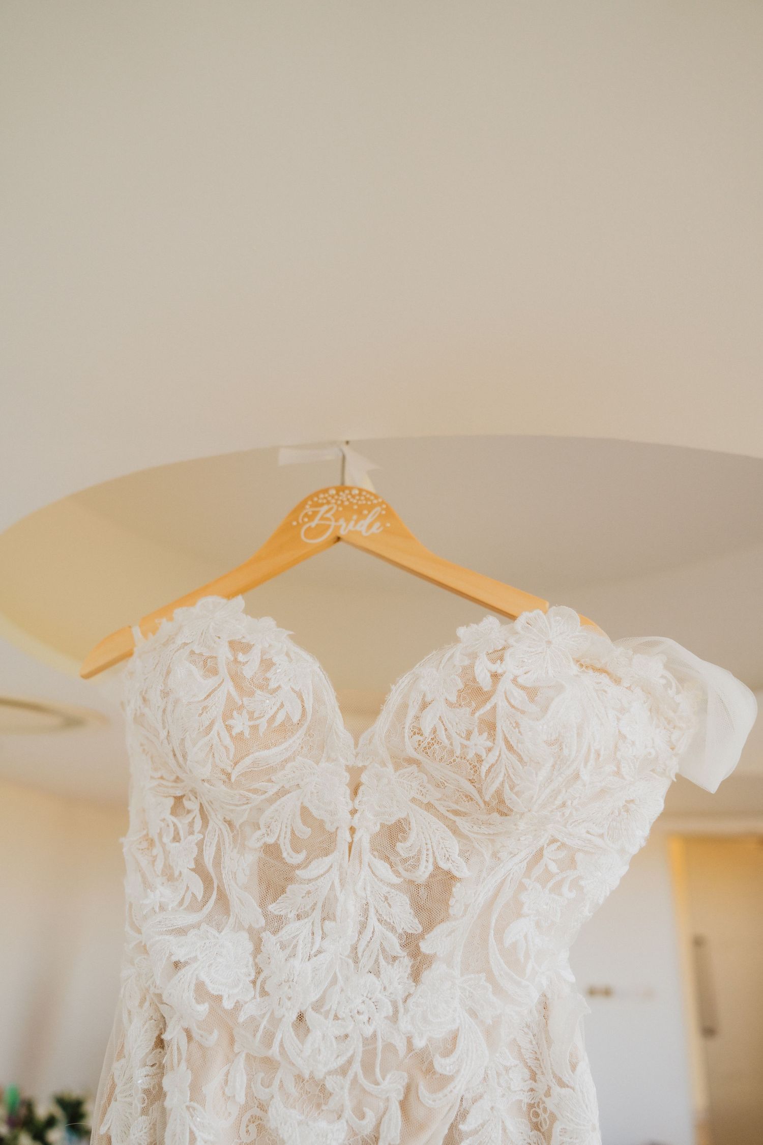 Stunning lace wedding dress with sweetheart neckline displayed on wooden hanger.