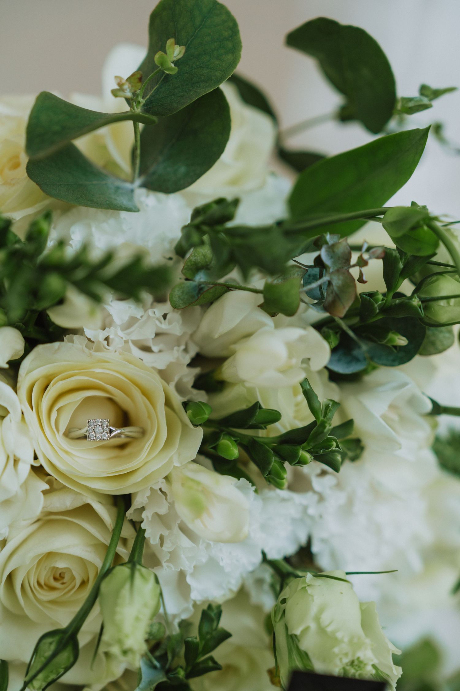 Close-up of cream roses and green foliage in a wedding bouquet arrangement.