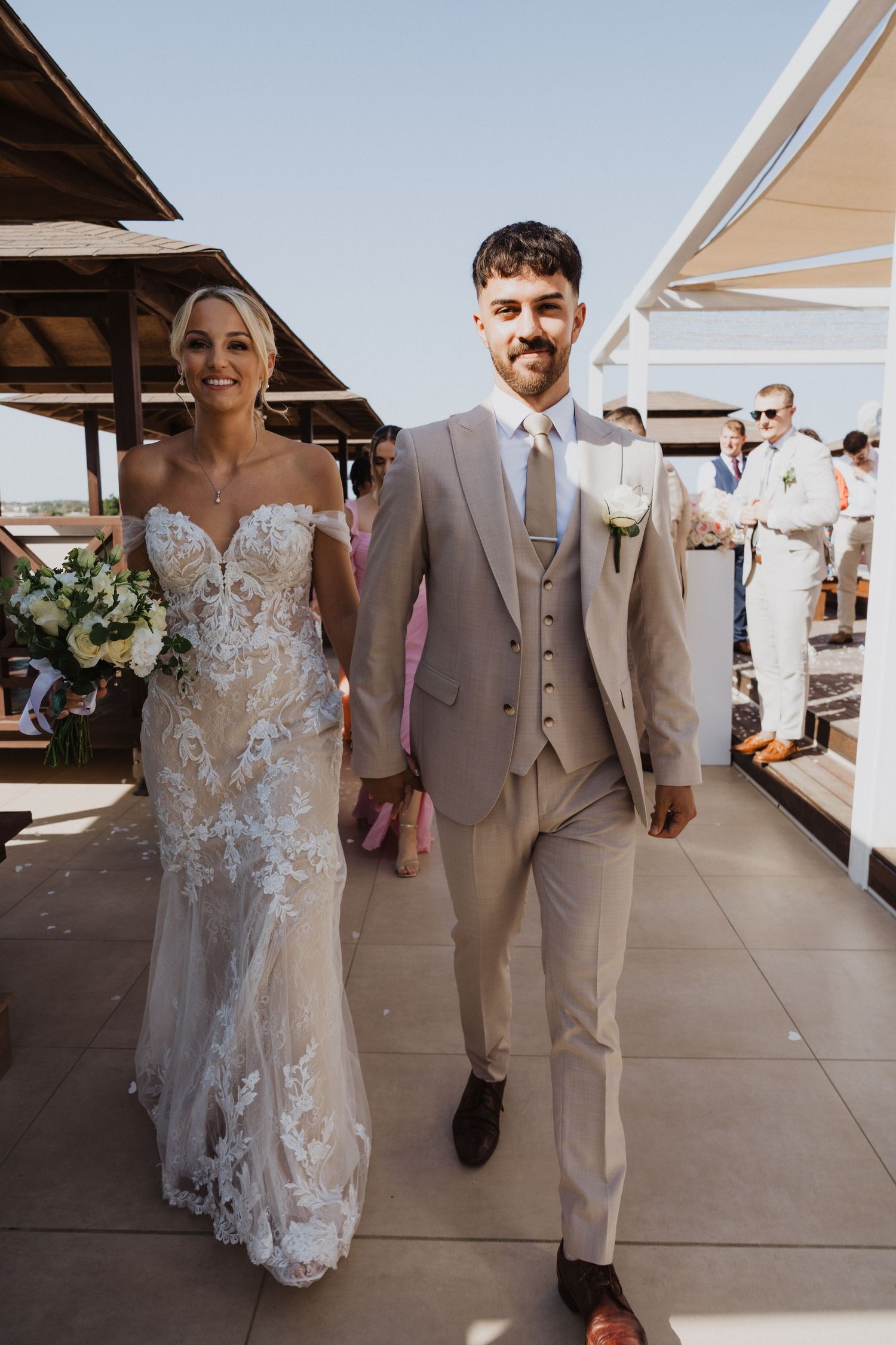 Couple walking together at their outdoor wedding venue in elegant attire.