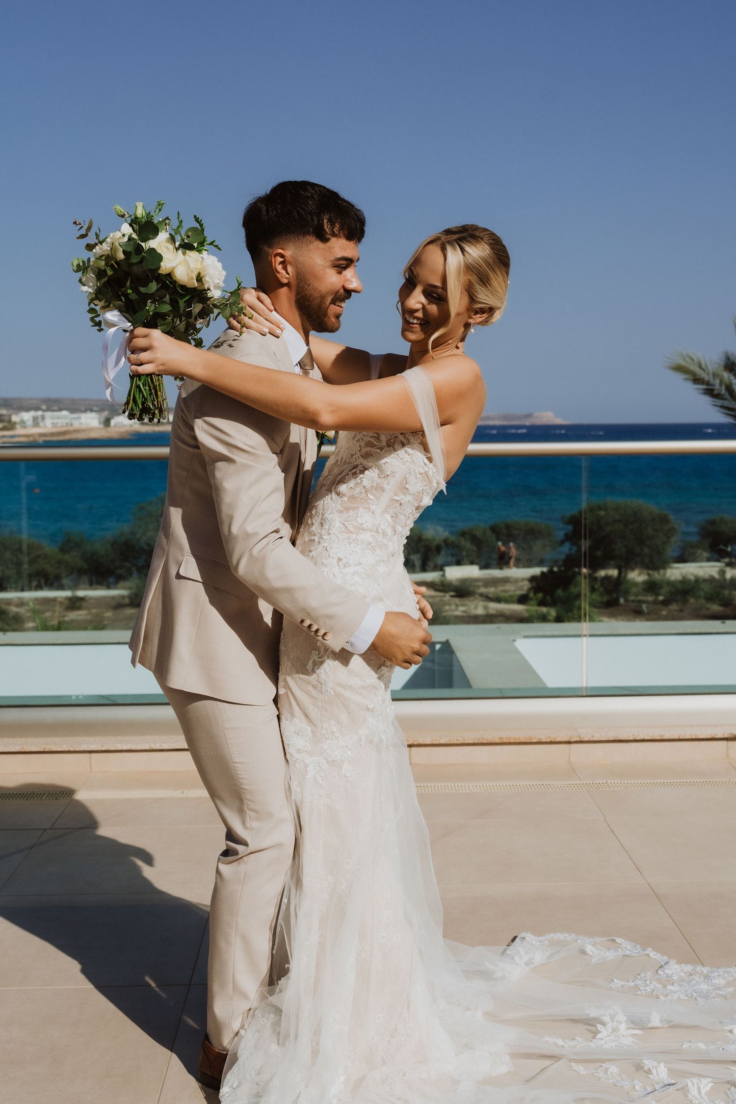 Couple sharing an intimate dance moment on a coastal terrace with ocean backdrop.