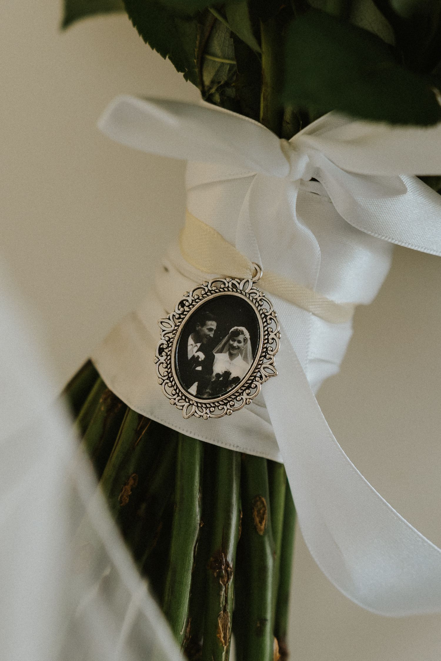 Memorial photo charm with white ribbon tied to a bouquet stem.