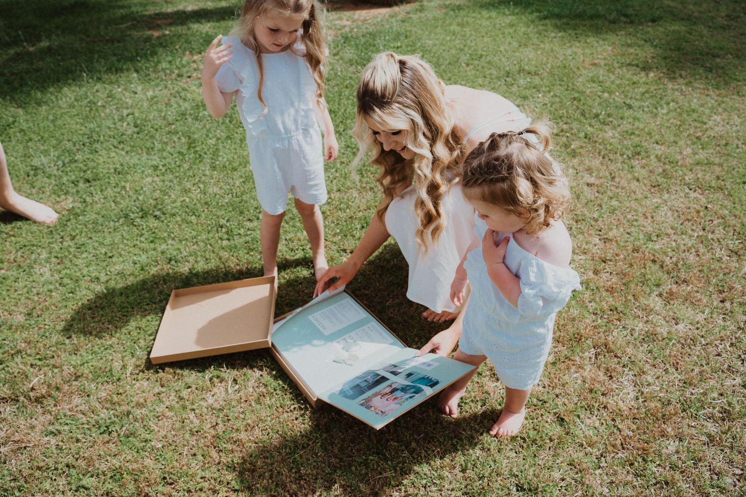 Group gathered on grass looking at a photo album or book together.