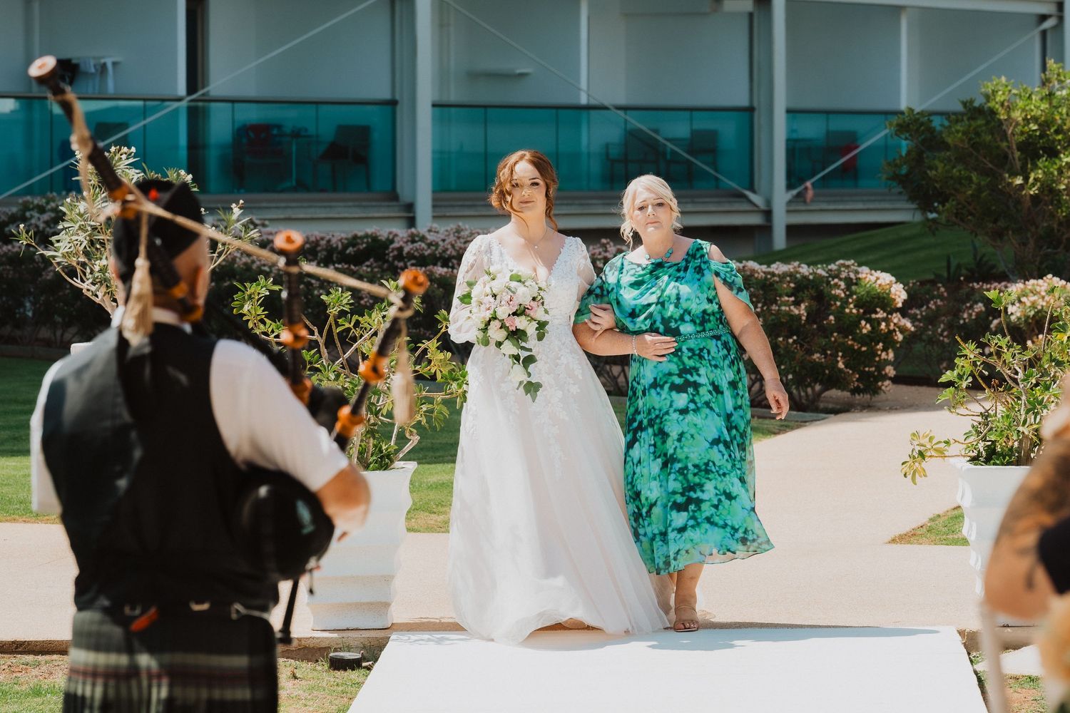 Outdoor wedding ceremony with photographer capturing moment on sunny day.