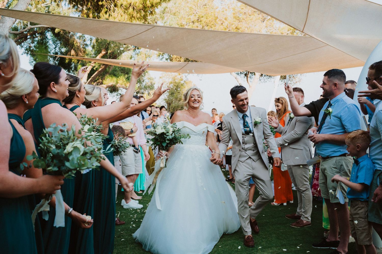 Wedding celebration on a garden lawn with guests throwing confetti during the recessional.
