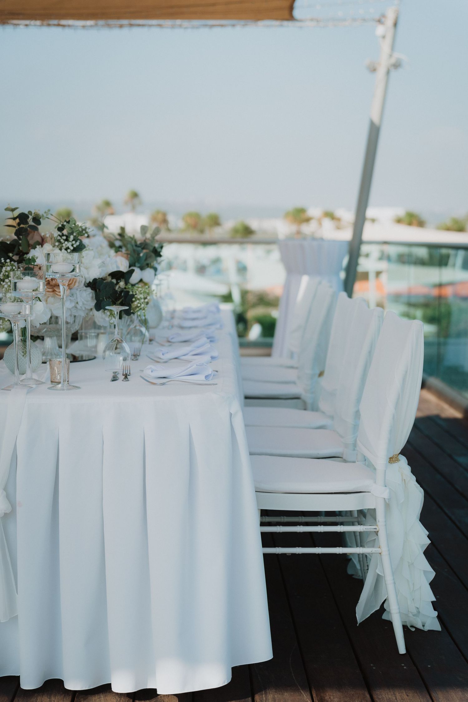Elegant outdoor wedding reception table with white linens and chairs overlooking a scenic view.