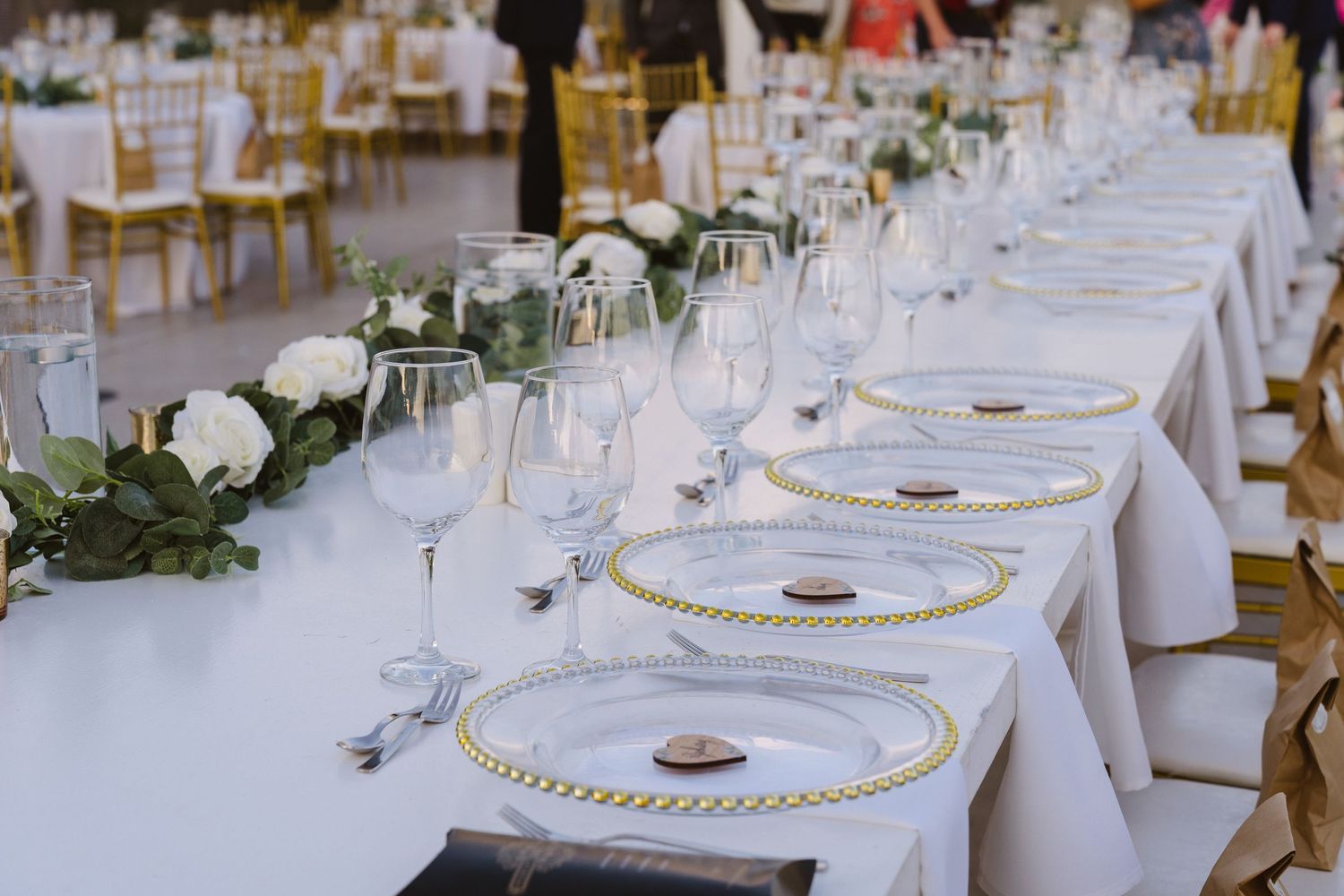 Formal table settings with gold-beaded charger plates and greenery centerpieces.