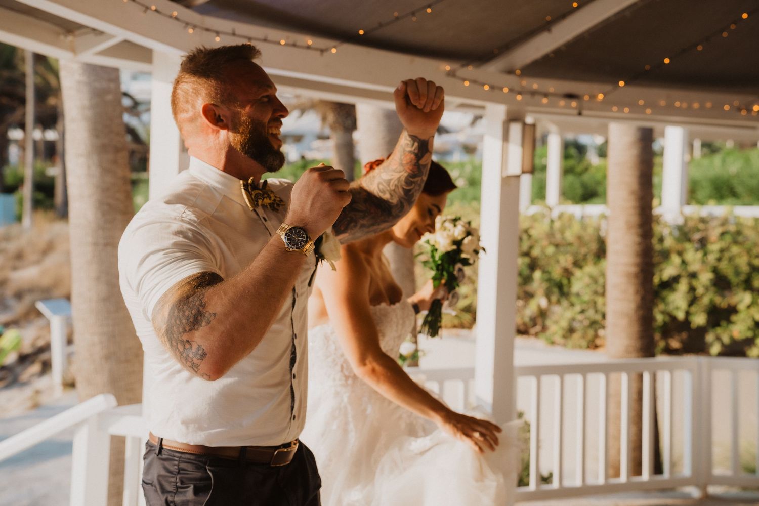 Dancing celebration moment on an outdoor terrace during sunset at wedding reception.