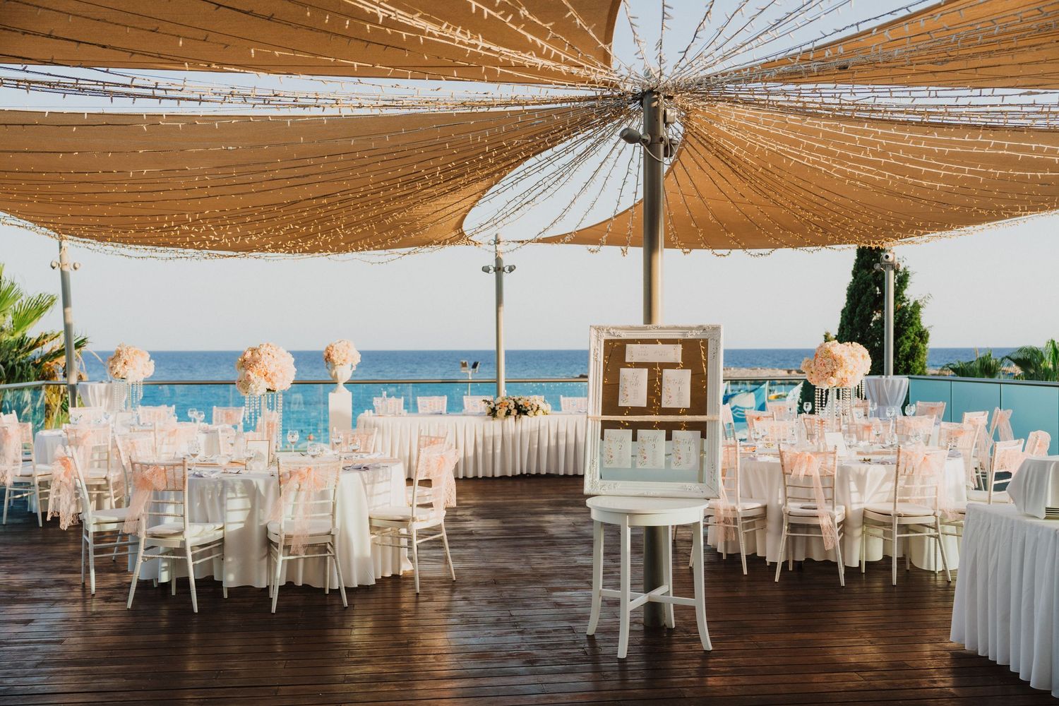 Panoramic view of an elegant outdoor wedding reception setup with white and gold decor.