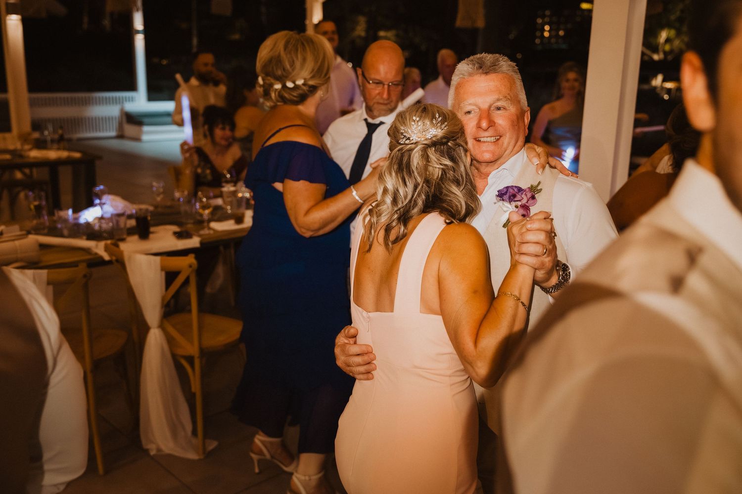 Wedding reception dance floor filled with guests celebrating under warm lighting.