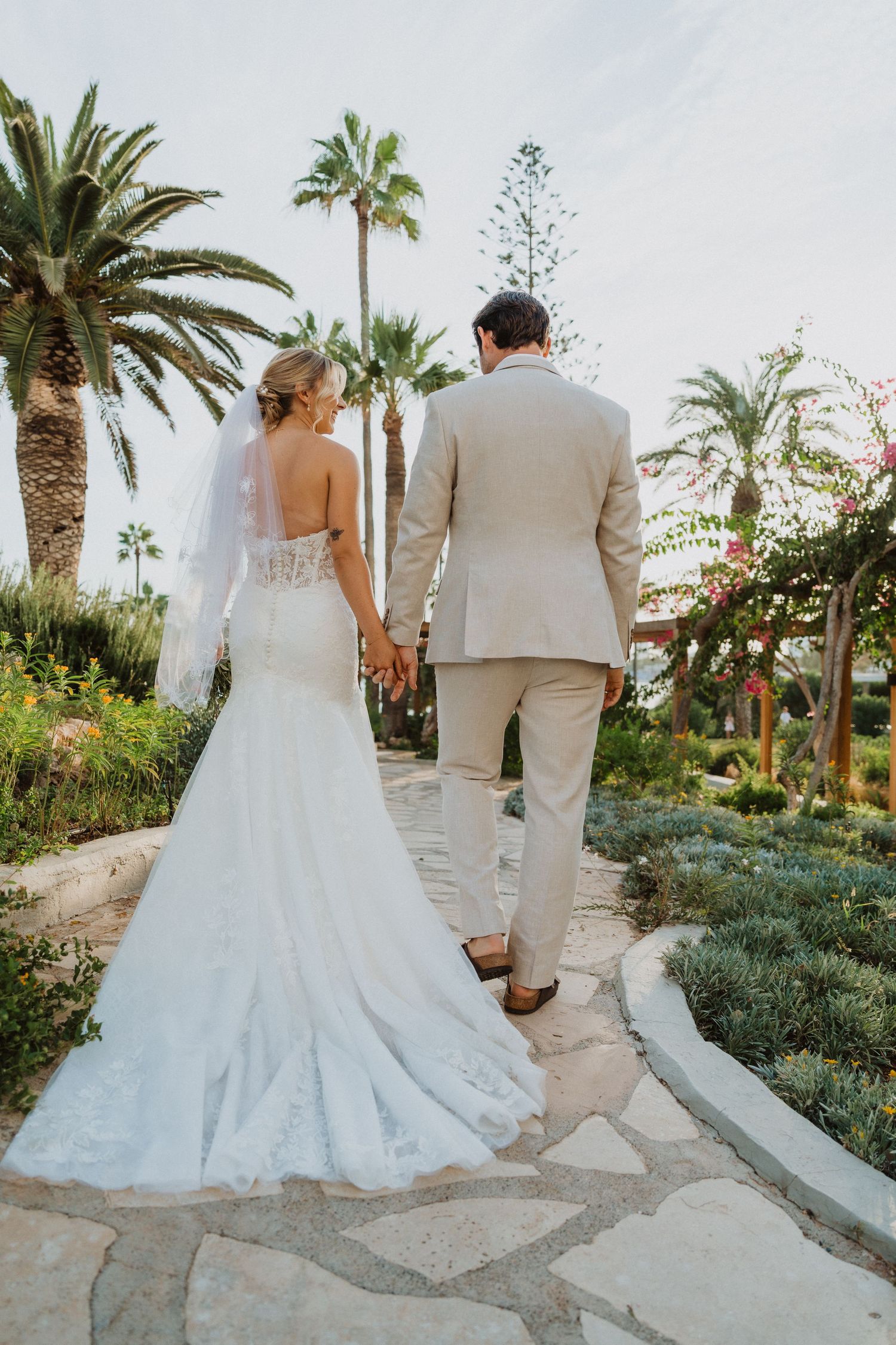 Couple walks down a winding stone pathway surrounded by tropical gardens.