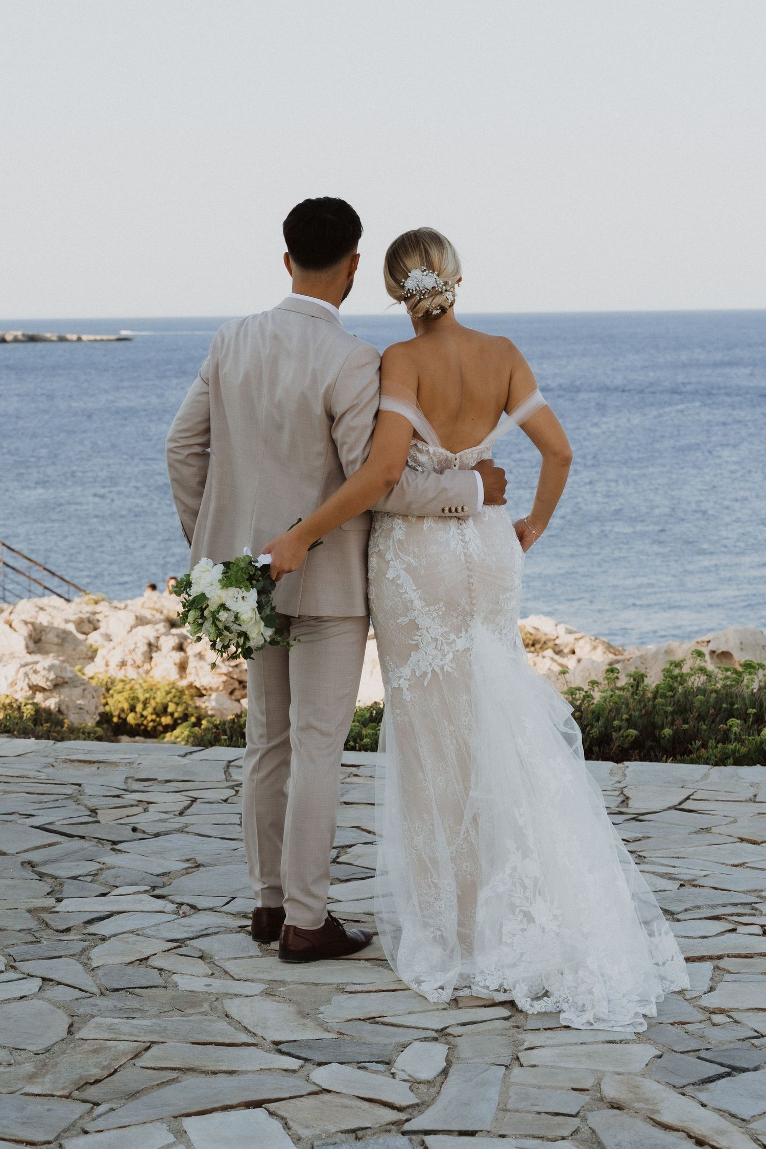Couple shares intimate moment on coastal terrace with ocean backdrop.