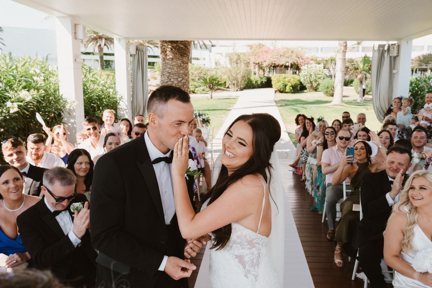 Wedding celebration with guests cheering during outdoor ceremony.