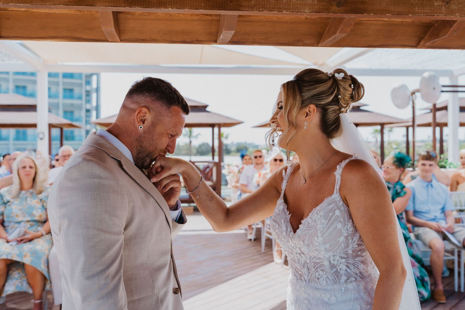 A couple shares an emotional first dance moment at their beach wedding reception with guests watching in the background.
