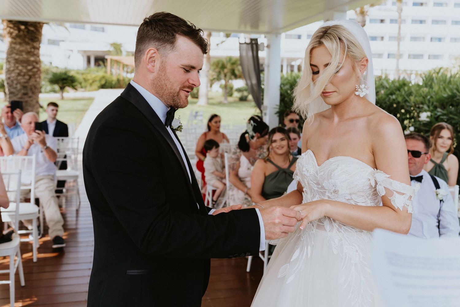 Intimate moment during ring exchange at outdoor wedding ceremony.