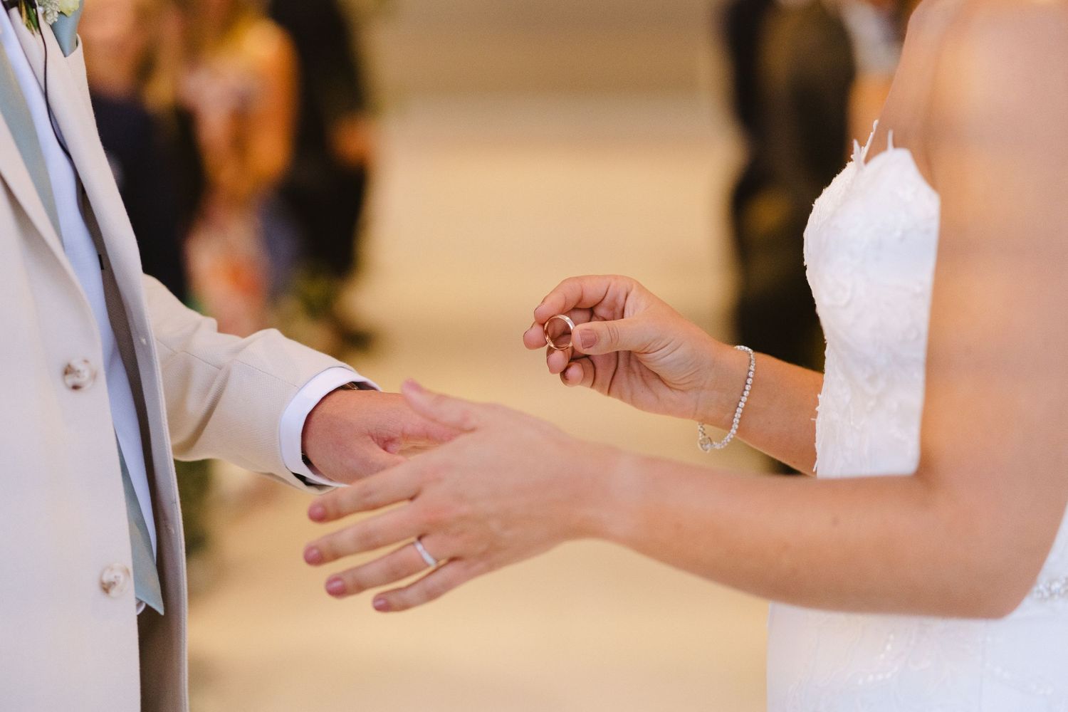 Close-up shot of hands during a wedding ring exchange ceremony.