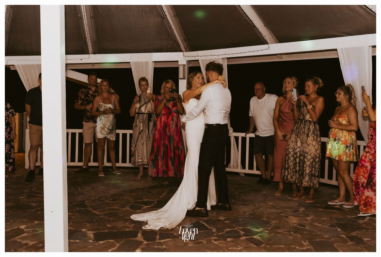 Couple dancing intimately at their wedding reception in warm evening lighting.