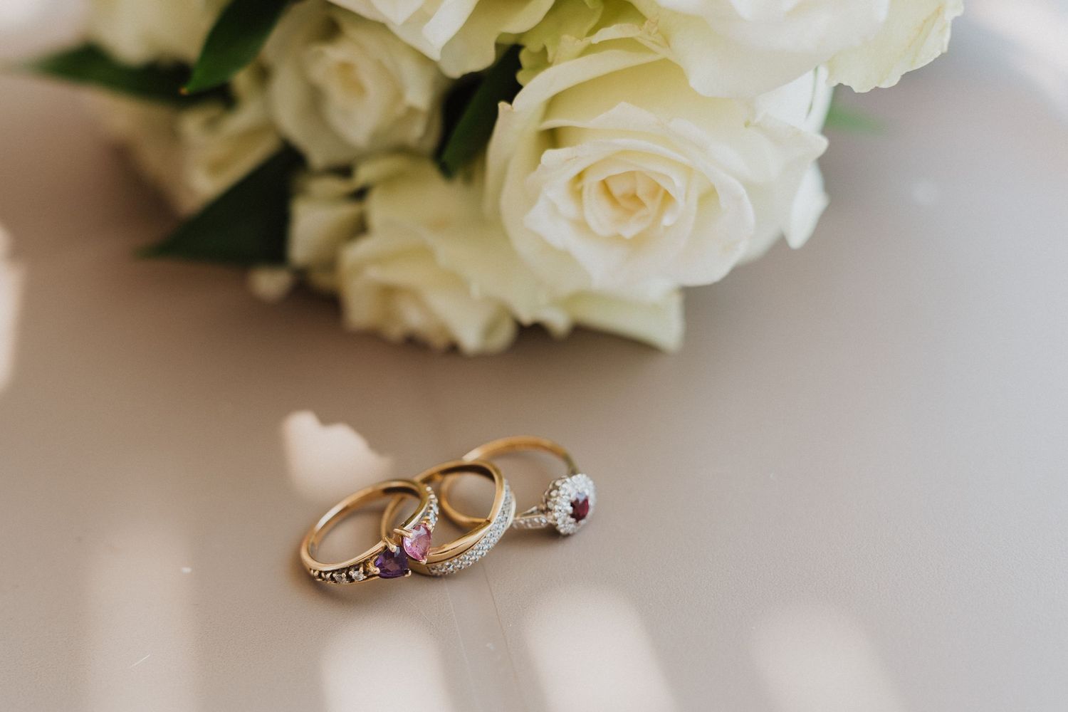 Wedding rings and white roses displayed on a light surface in a romantic arrangement.