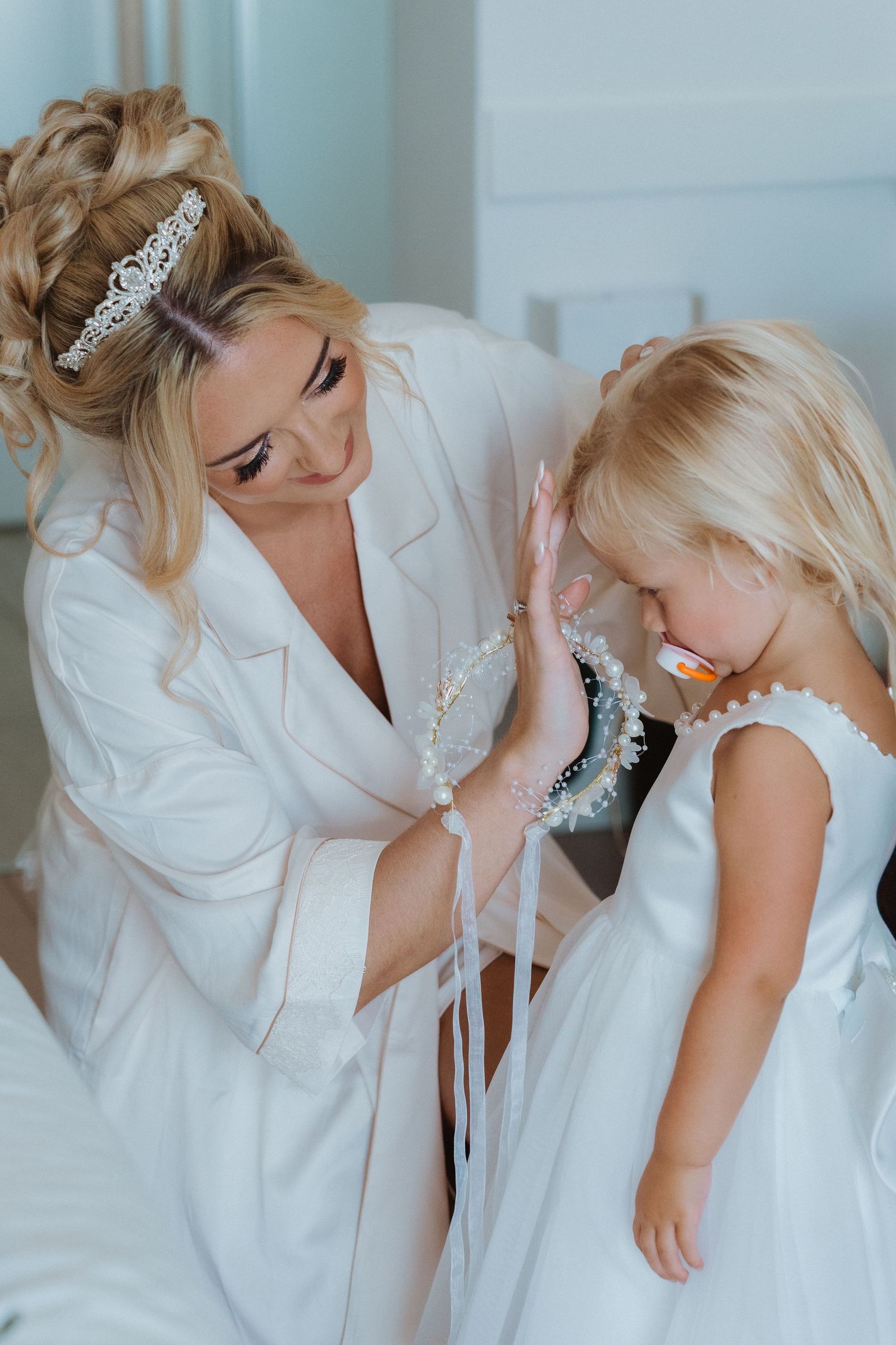 Sweet tender moment of getting ready for a special celebration with white dresses and delicate accessories.