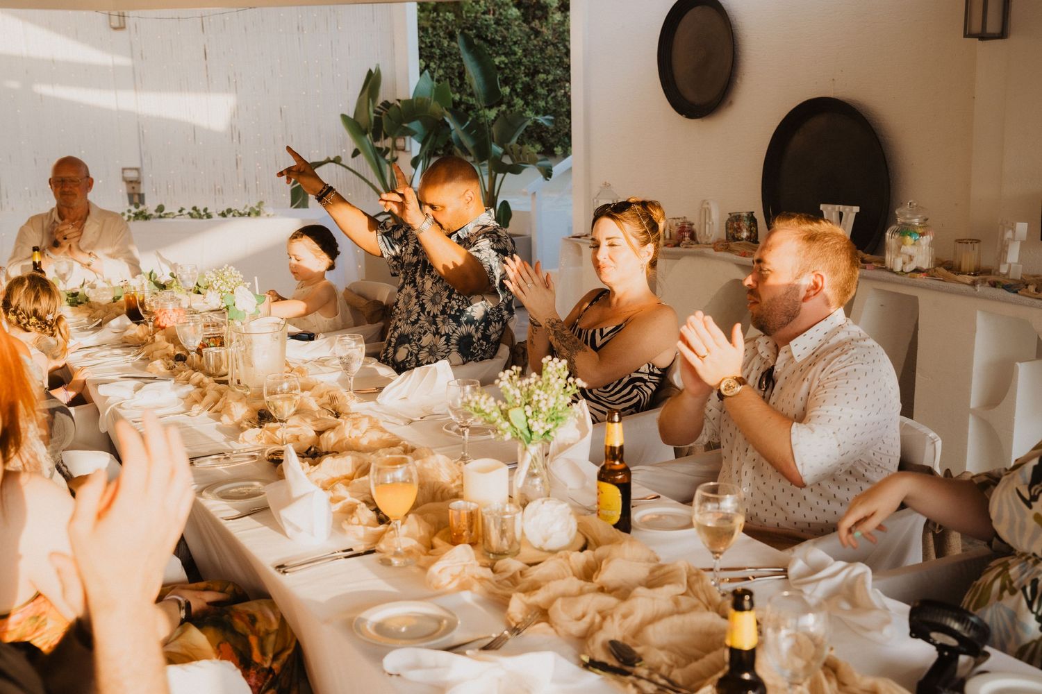Wedding reception guests raising glasses in a toast during dinner celebration.