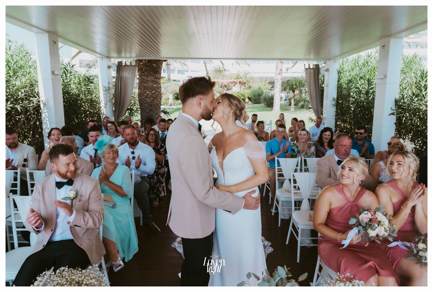 Romantic wedding moment captured in a covered outdoor venue with seated guests.