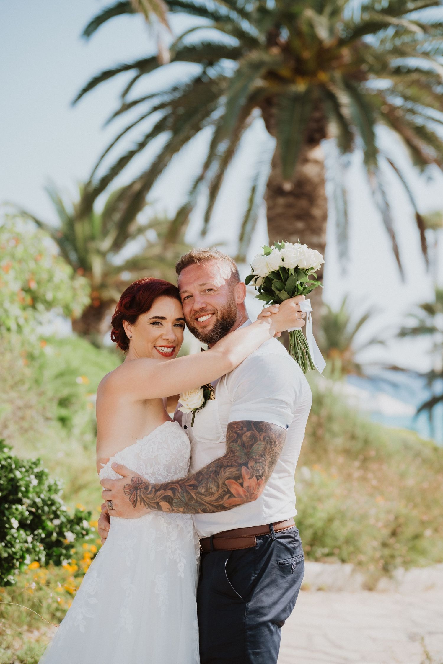 A joyful wedding moment captured against a backdrop of swaying palm trees and blue skies.