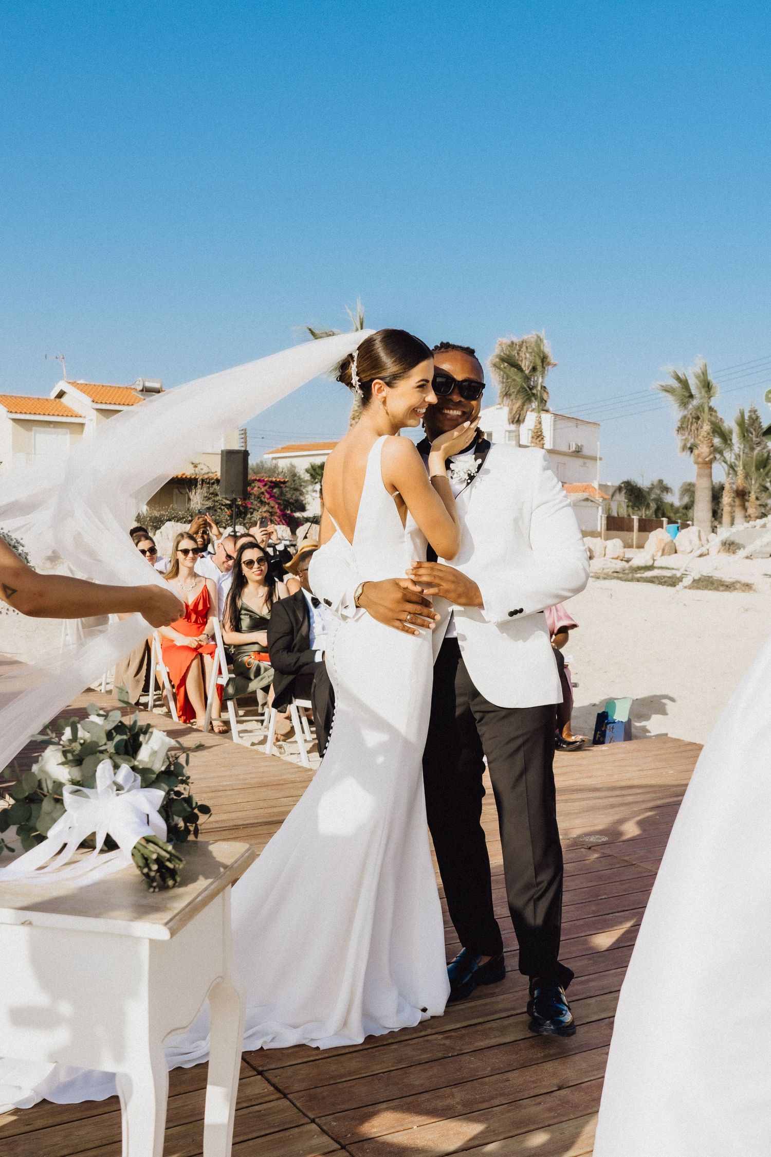 Newlyweds sharing a romantic dance on a wooden deck by the ocean.