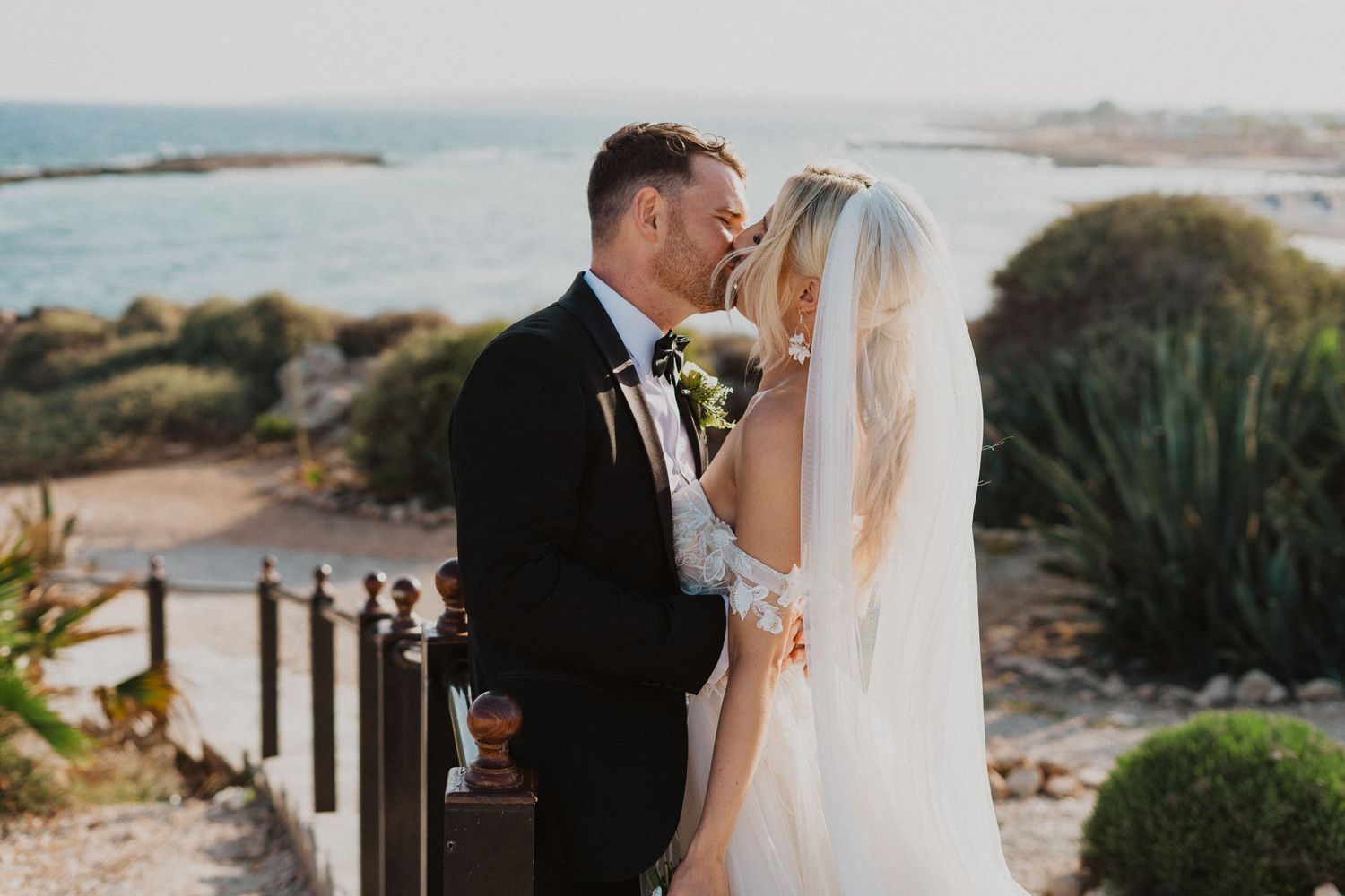 Romantic seaside wedding portrait with coastal Mediterranean landscape in background.