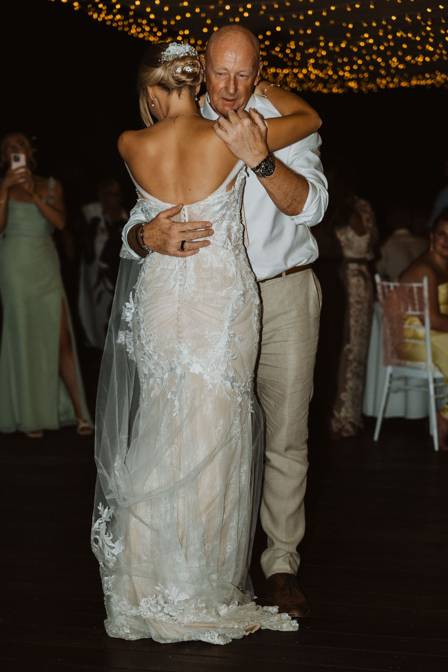 Couple shares an intimate dance moment at their wedding reception under twinkling lights.