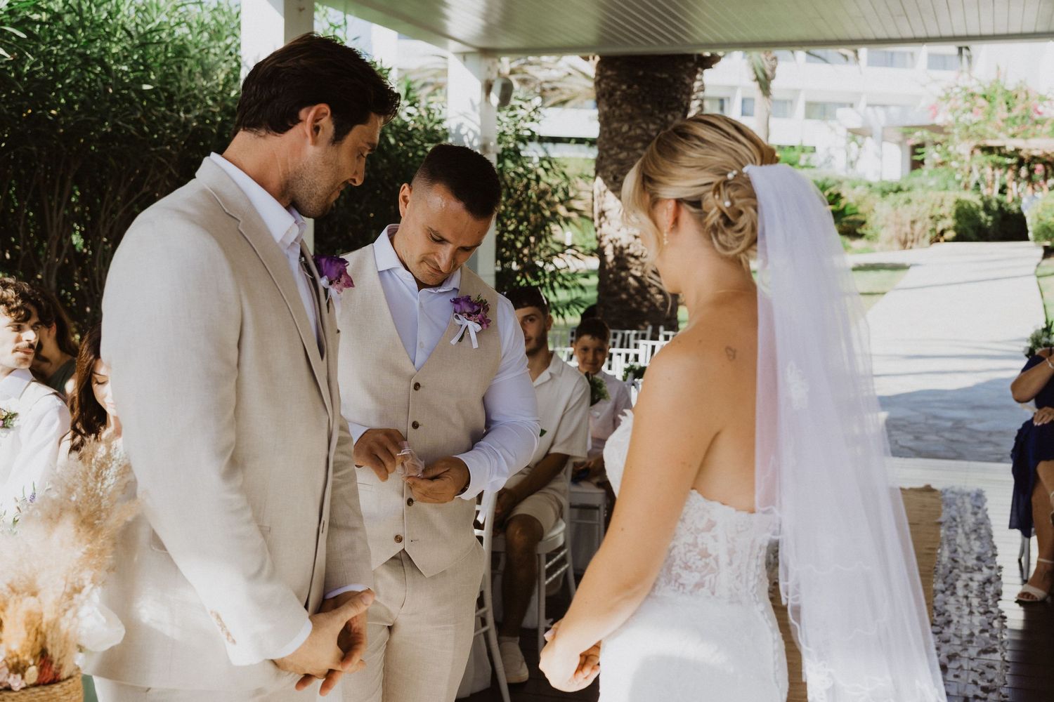 Wedding guests gather under a white-pillared pavilion to celebrate the newlyweds' special moment.