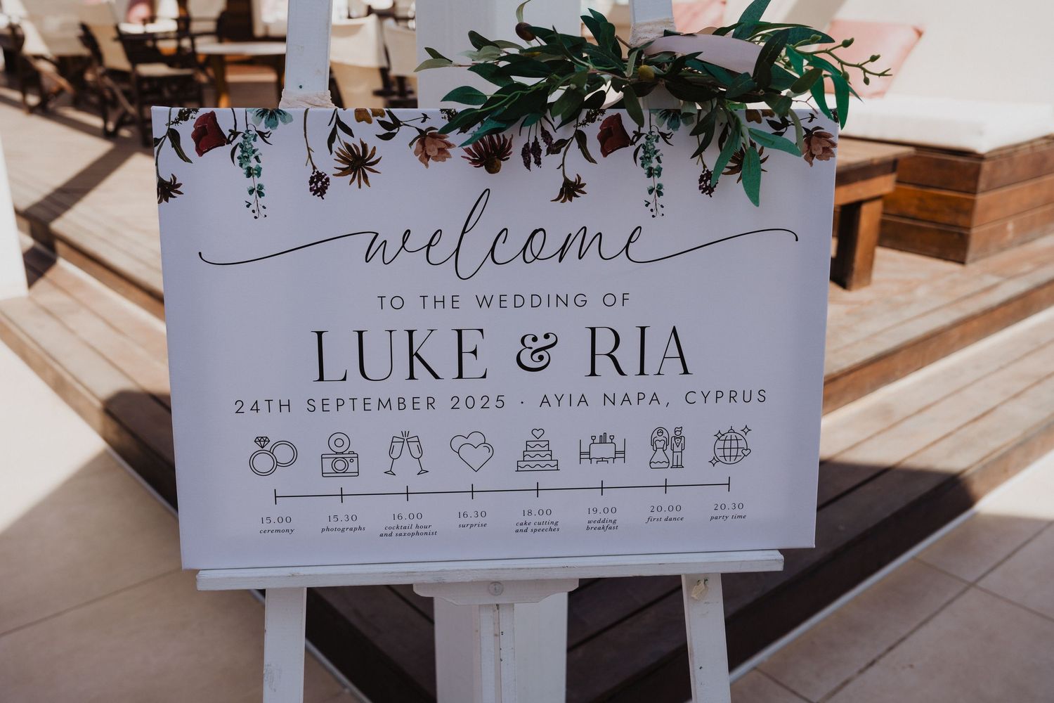 Wedding welcome sign and details decorated with greenery and floral elements.