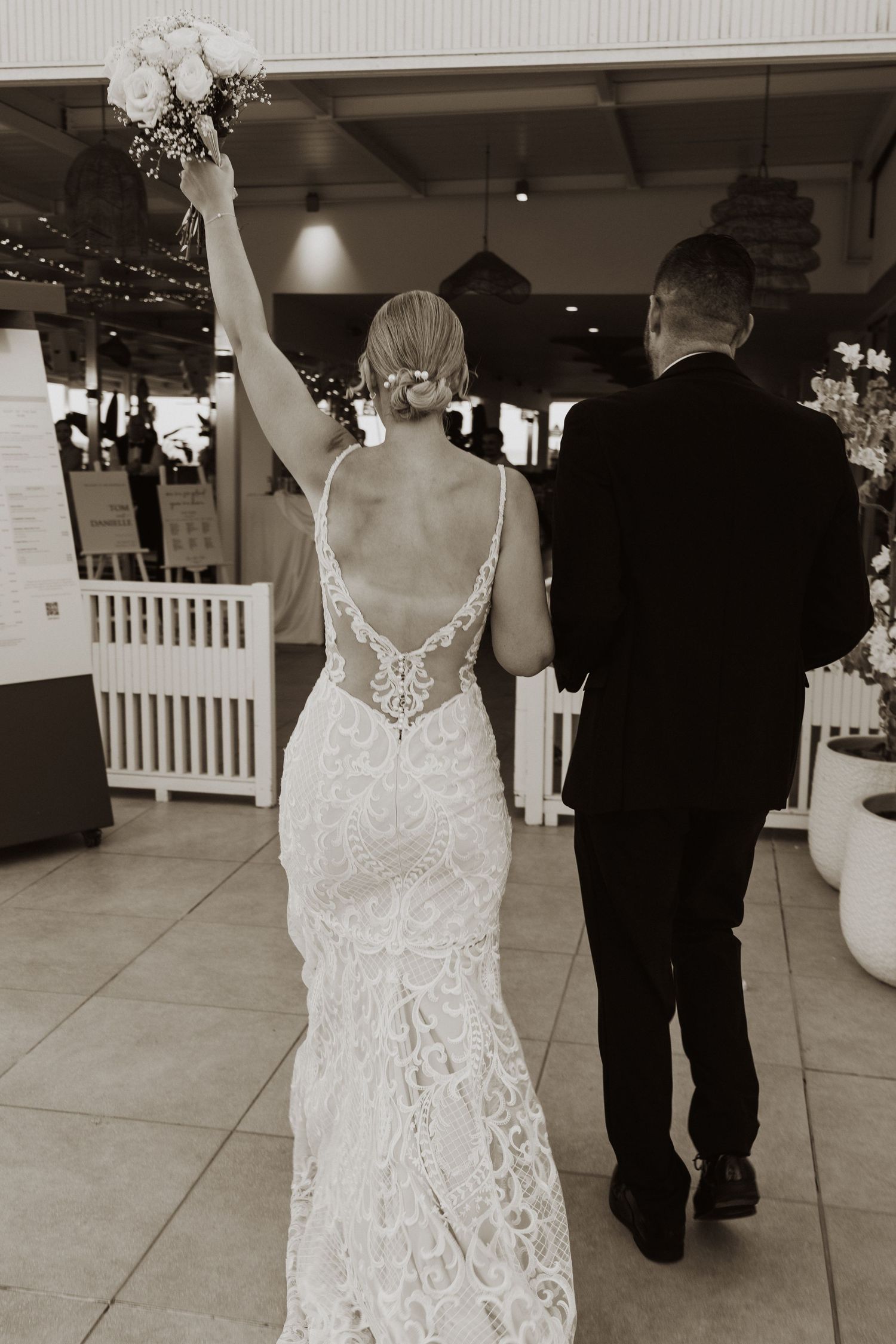 Wedding couple walking through an elegant indoor venue in formal attire.
