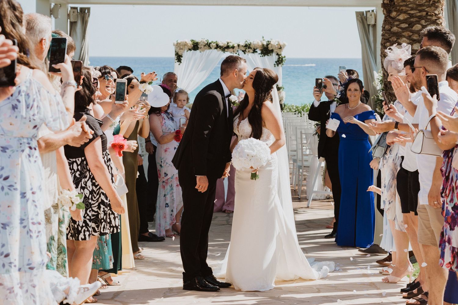 Wedding guests line up on outdoor patio to celebrate newlyweds.