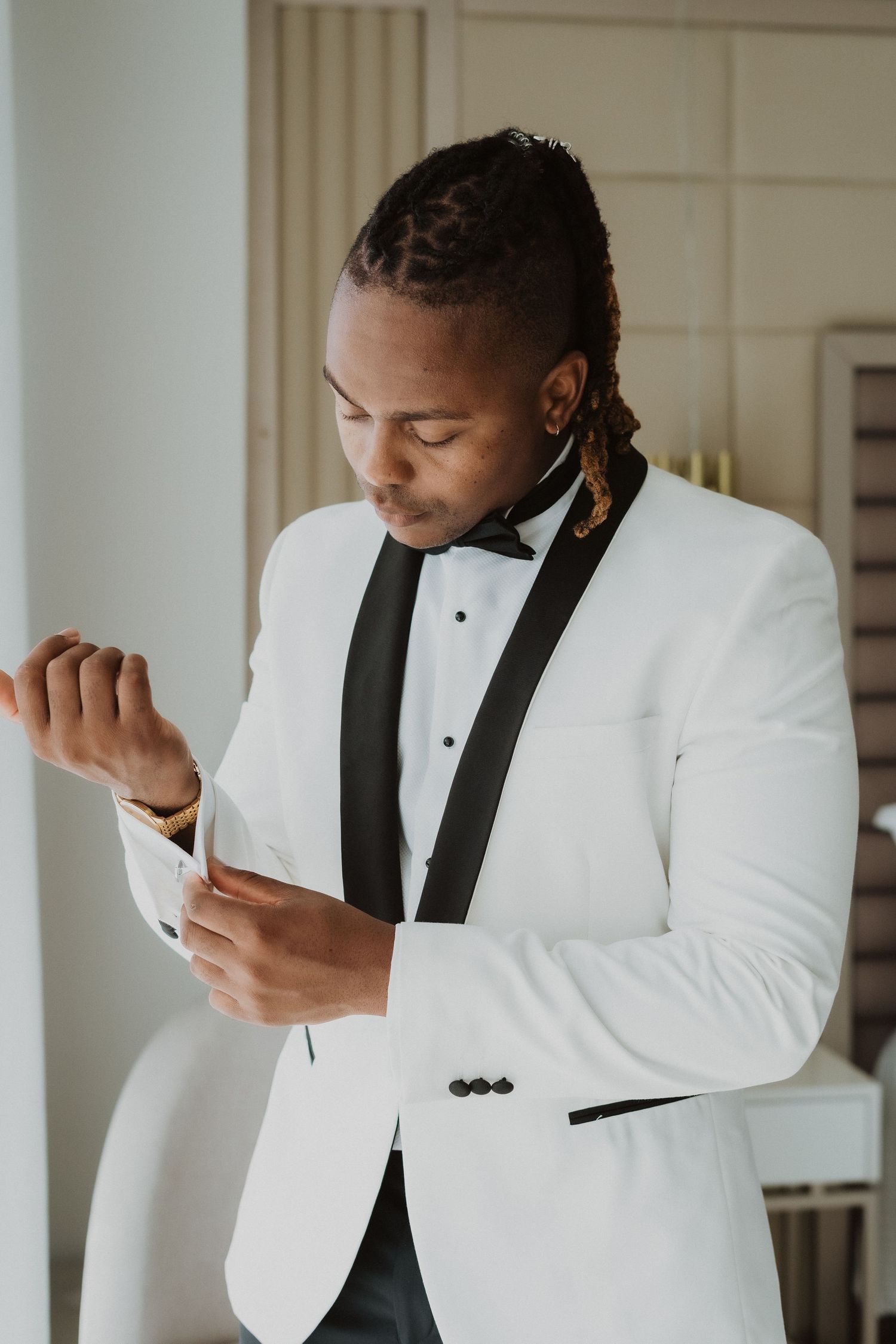 A person in formal attire adjusts their cufflinks before an event.