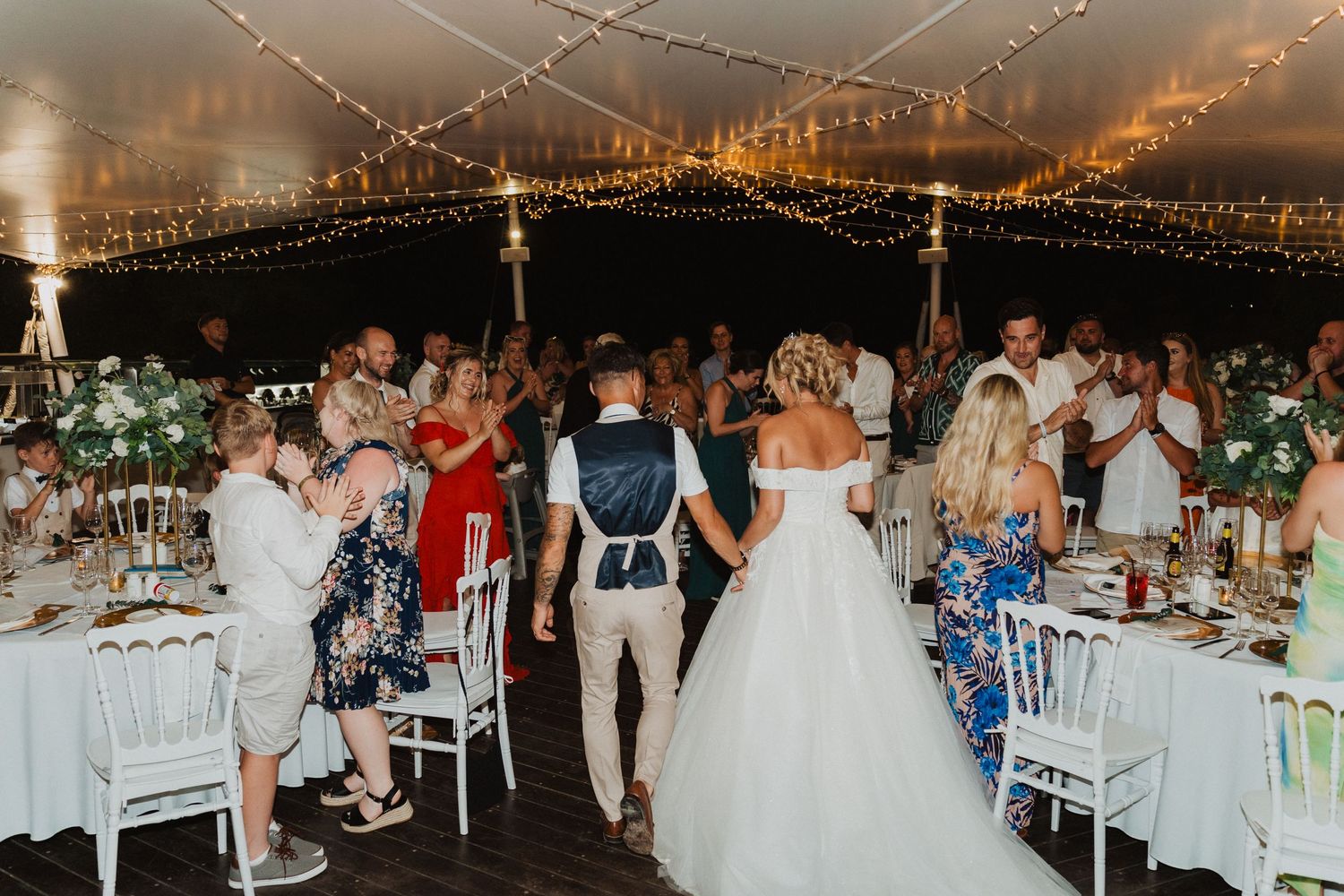 Wedding reception celebration under a lit canopy showing tables decorated with festive party decor and lights.